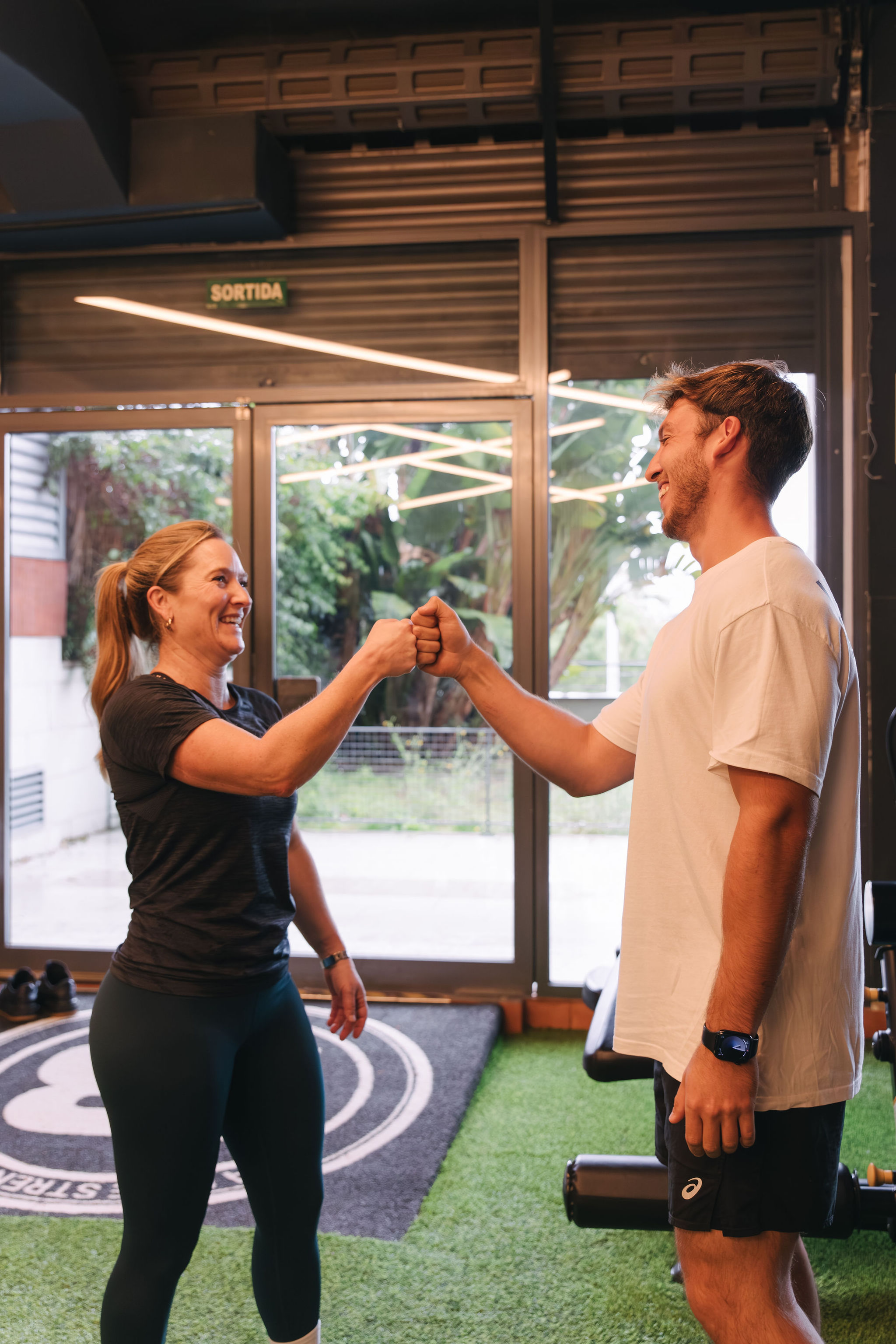 Entrenador personal felicitando a clienta en La Base Strength, Sitges