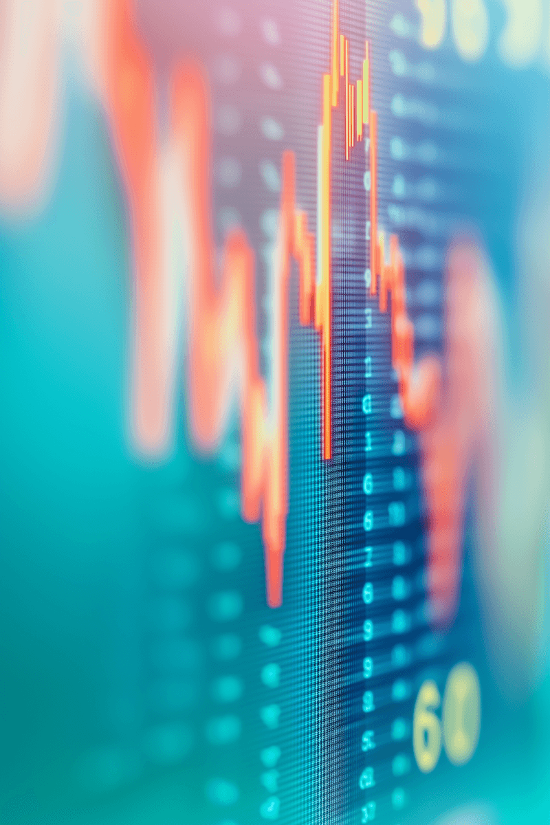 Close-up of a digital screen displaying glowing orange stock charts.