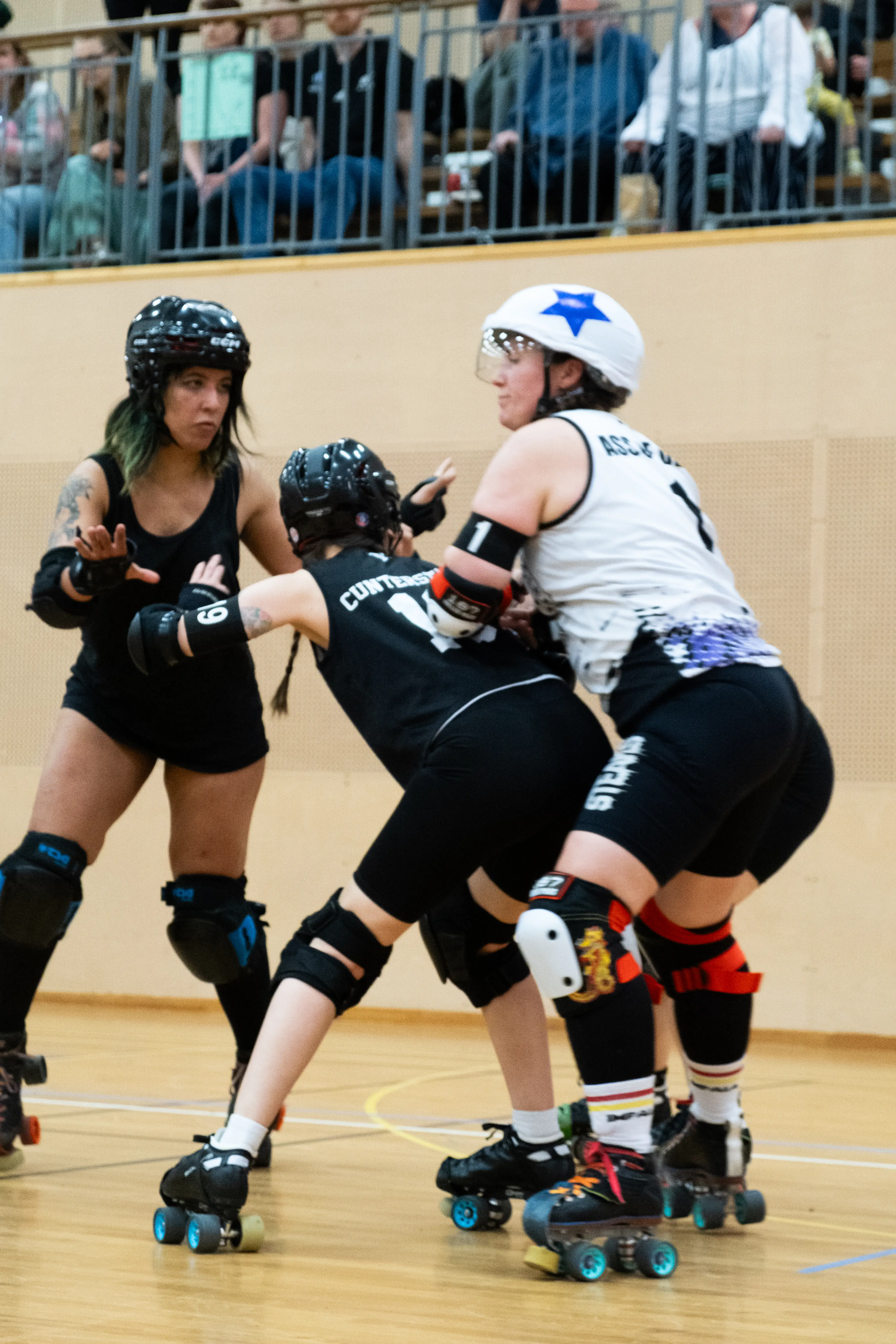 Three roller derby players tackling each other.