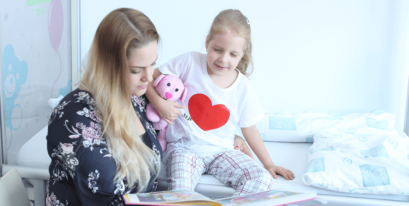 Édesanya gyermekével, mesét olvasnak az ágyon ülve