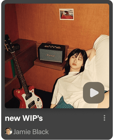 Smiling young man with short hair poses against a dark background, wearing a green button-up shirt.