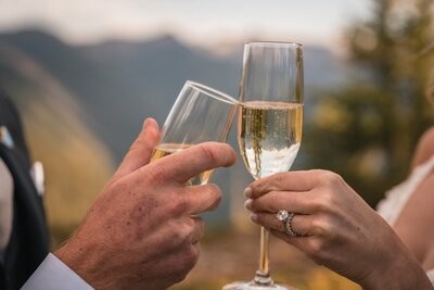 Close-up of champagne glasses touching during a toast, with wedding rings visible.