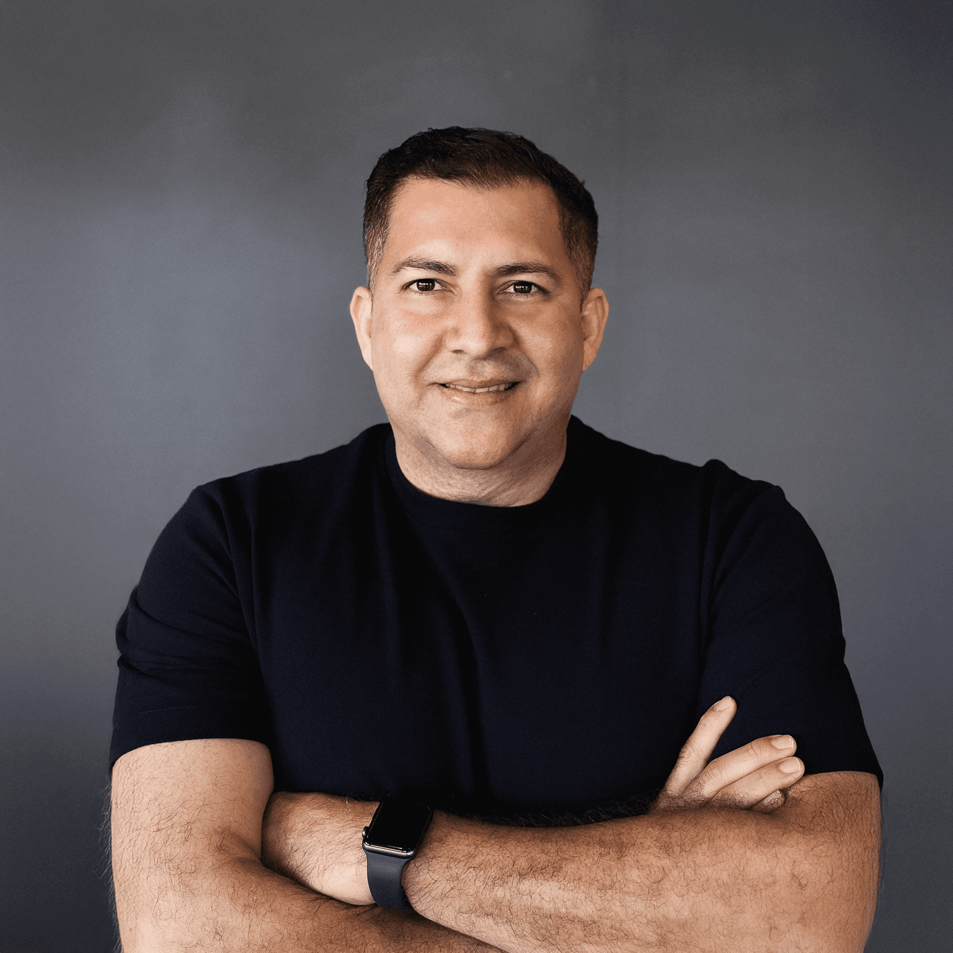 A man in a brown blazer and a woman in a light sweater sit at a desk with a laptop, discussing something. The room is dimly lit, creating a focused atmosphere.