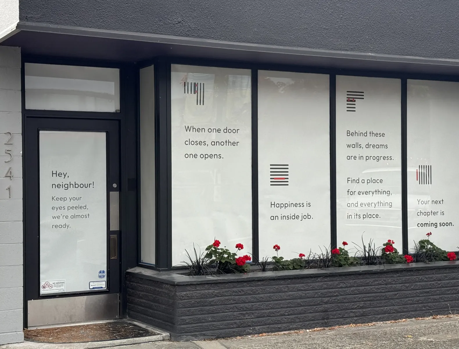 A real world photo of the storefont window covers saying "Hey Neighbour, we're almost ready."