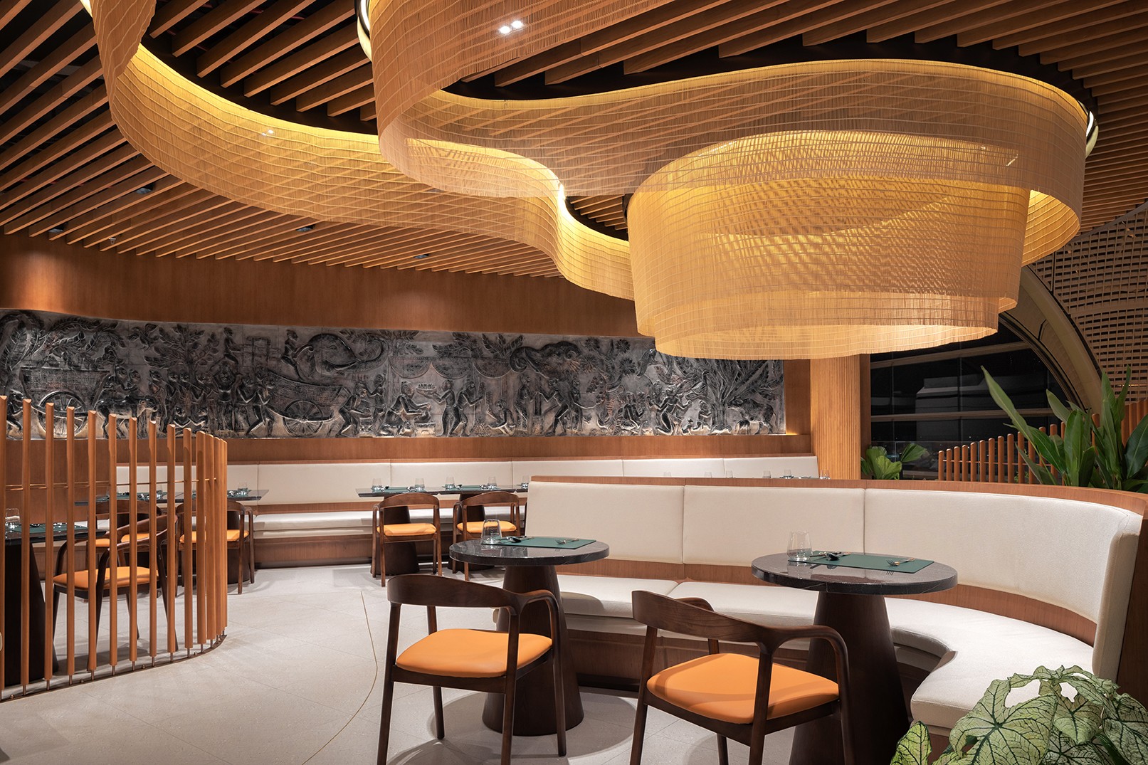 Curved banquette seating beneath a sculptural golden ceiling in Malis Restaurant at Techo International Airport