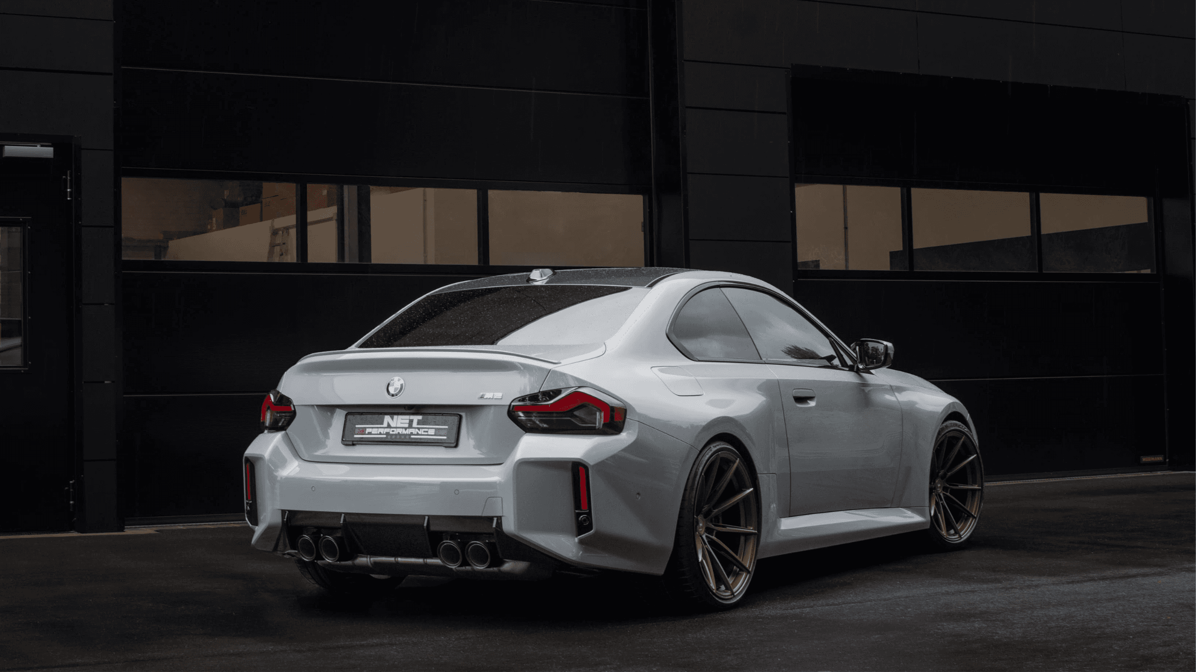 Heckansicht eines grauen BMW M2 CS mit bronzefarbenen Felgen