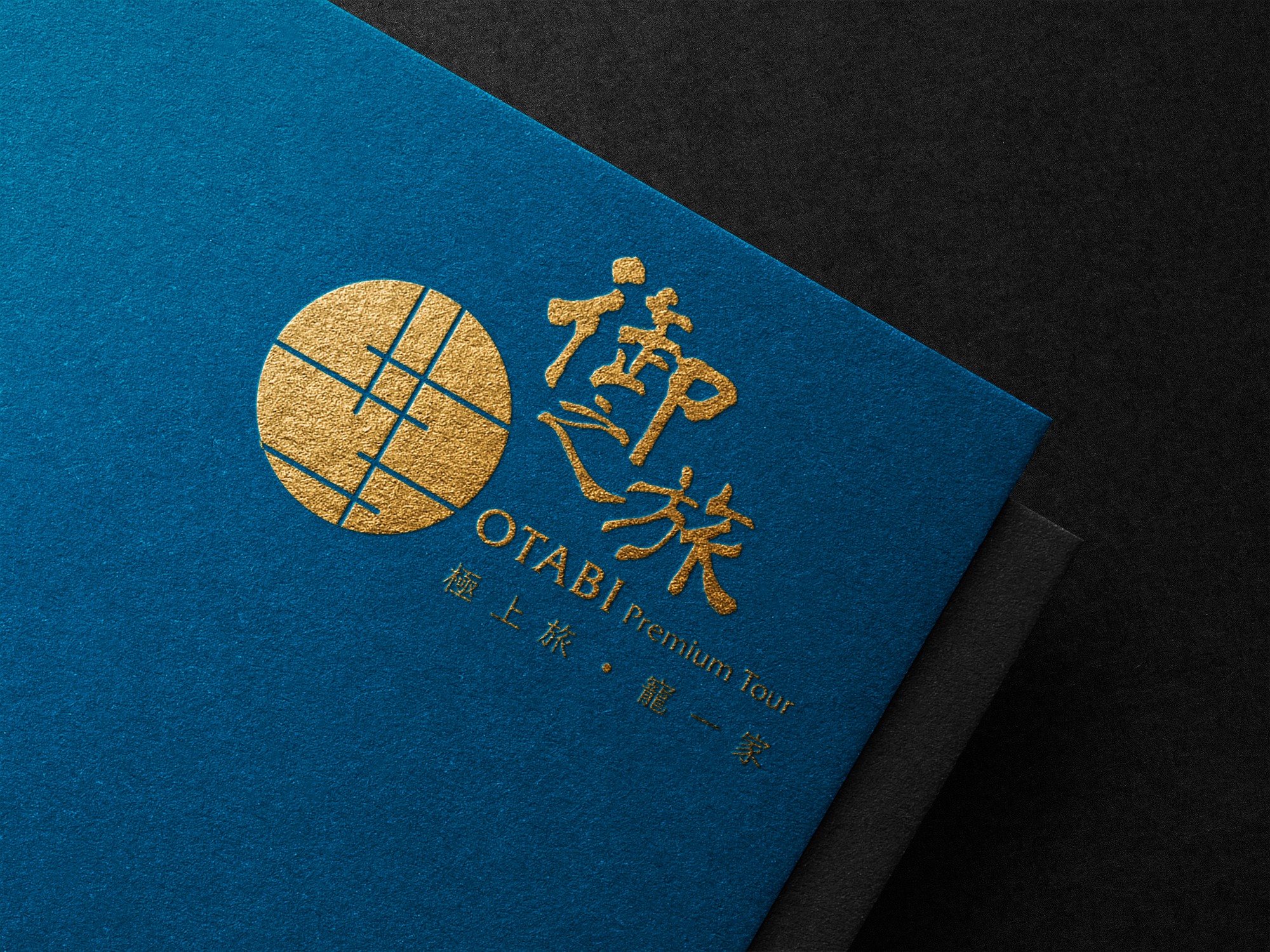這張圖像展示了御之旅的品牌識別設計,燙金色的標誌和文字印在藍色紙上,突顯出品牌的高端和專業形象。