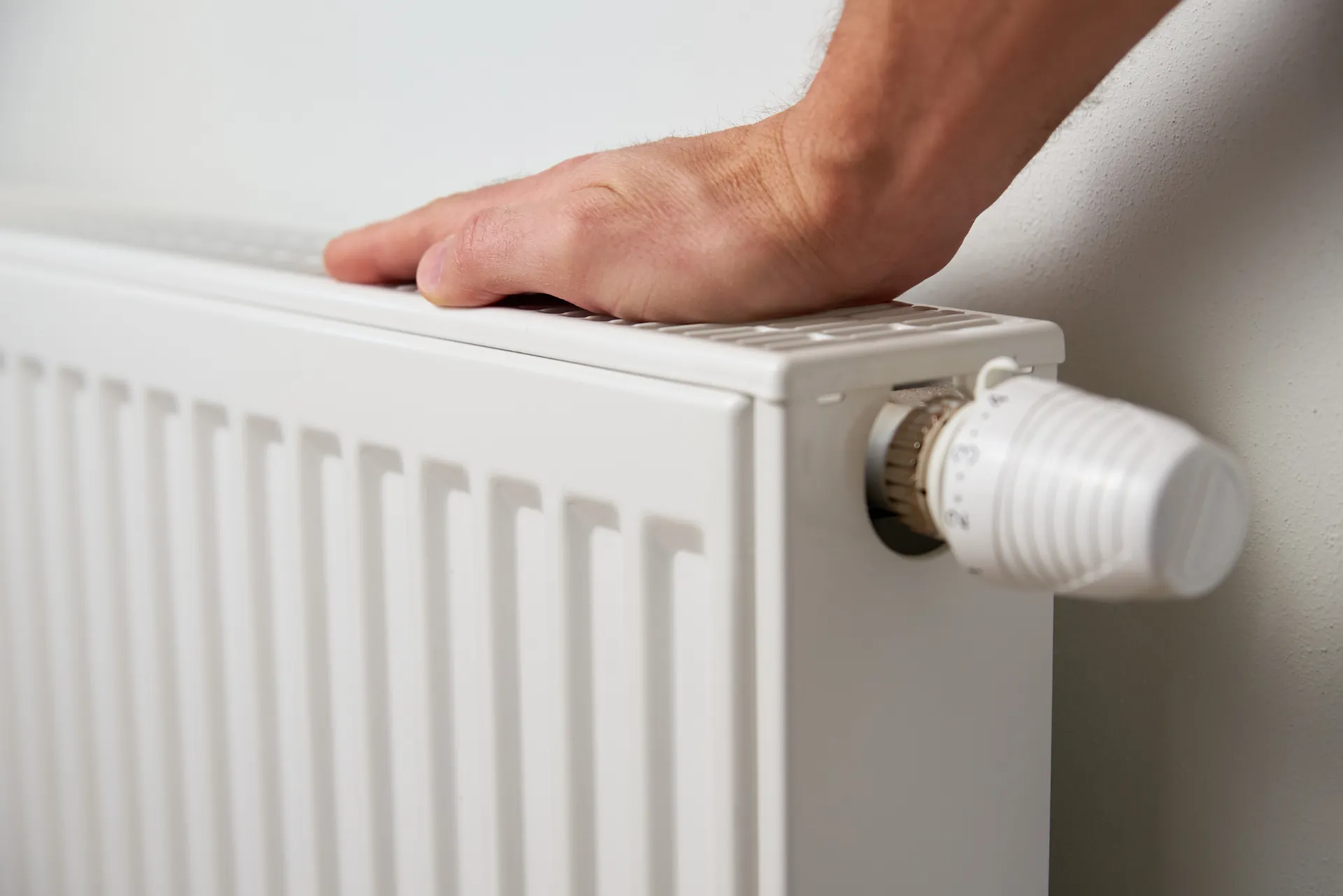 Eine Person die gerade die Hand auf einem weißen Heizkörper hat.