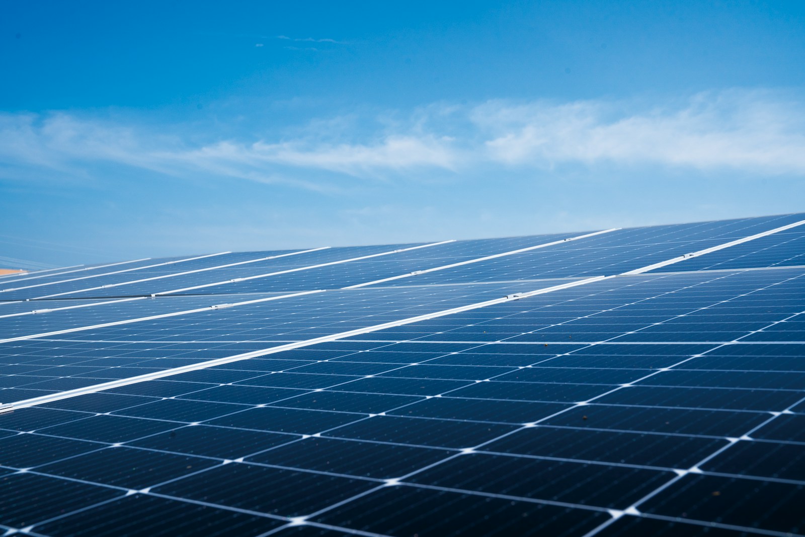 Rows of solar panels stretching towards a blue sky
