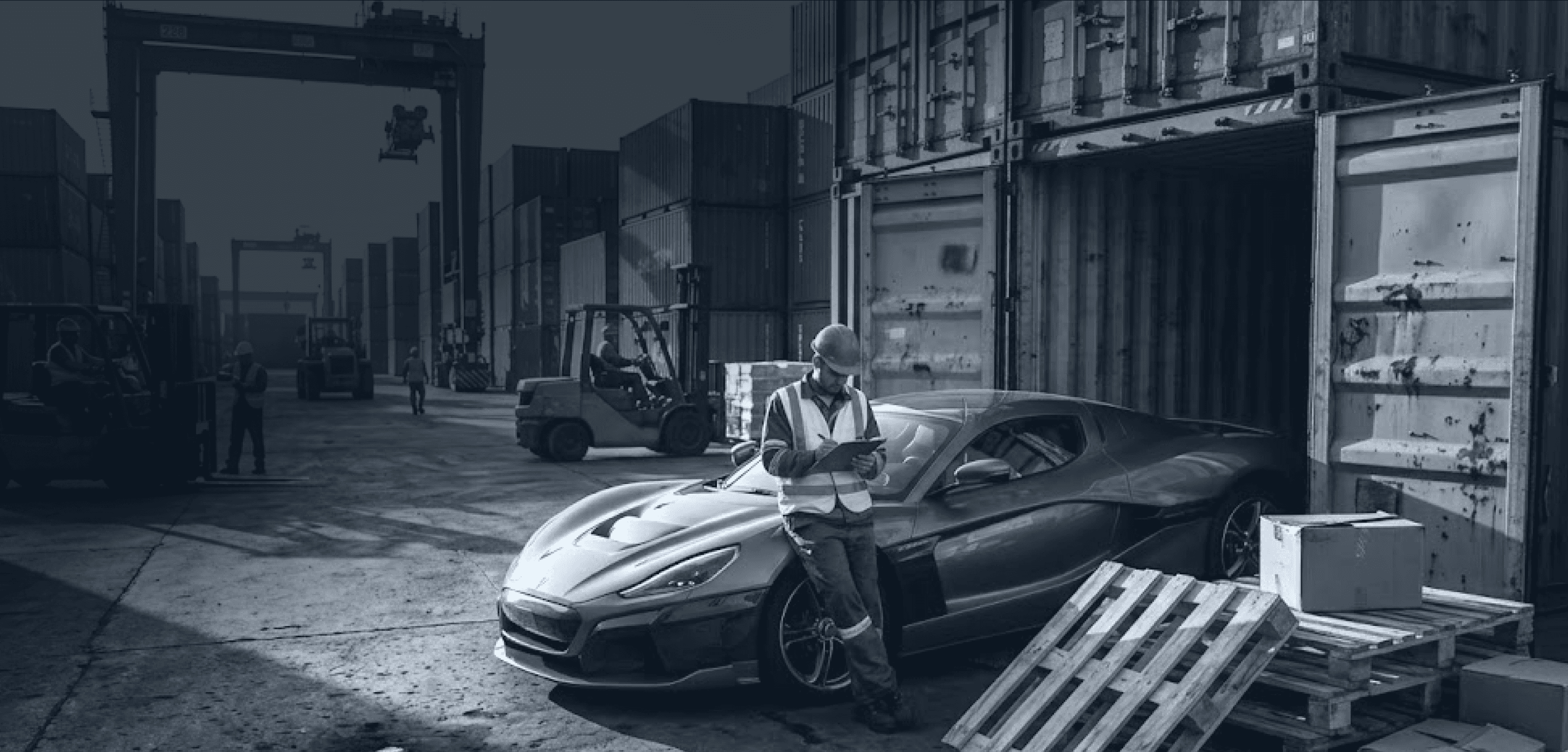 Logistics worker using tablet beside sports car in active container yard with forklifts operating
