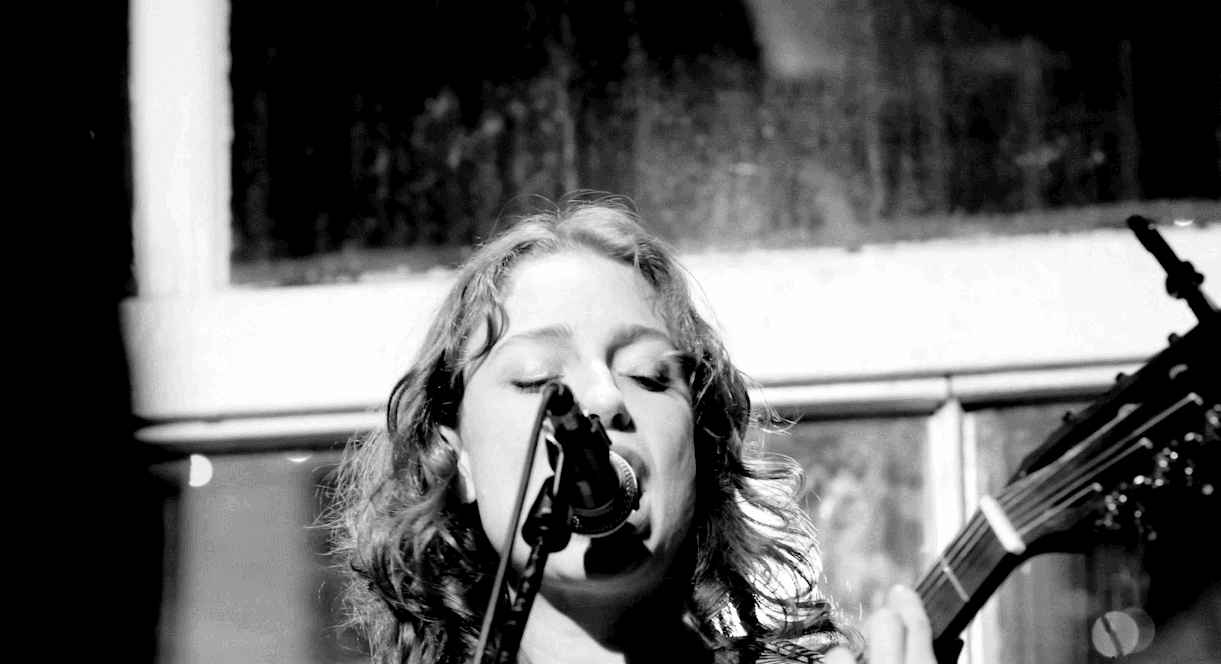 black and white film frame of a singer songwriter at Rhythms in Olympia