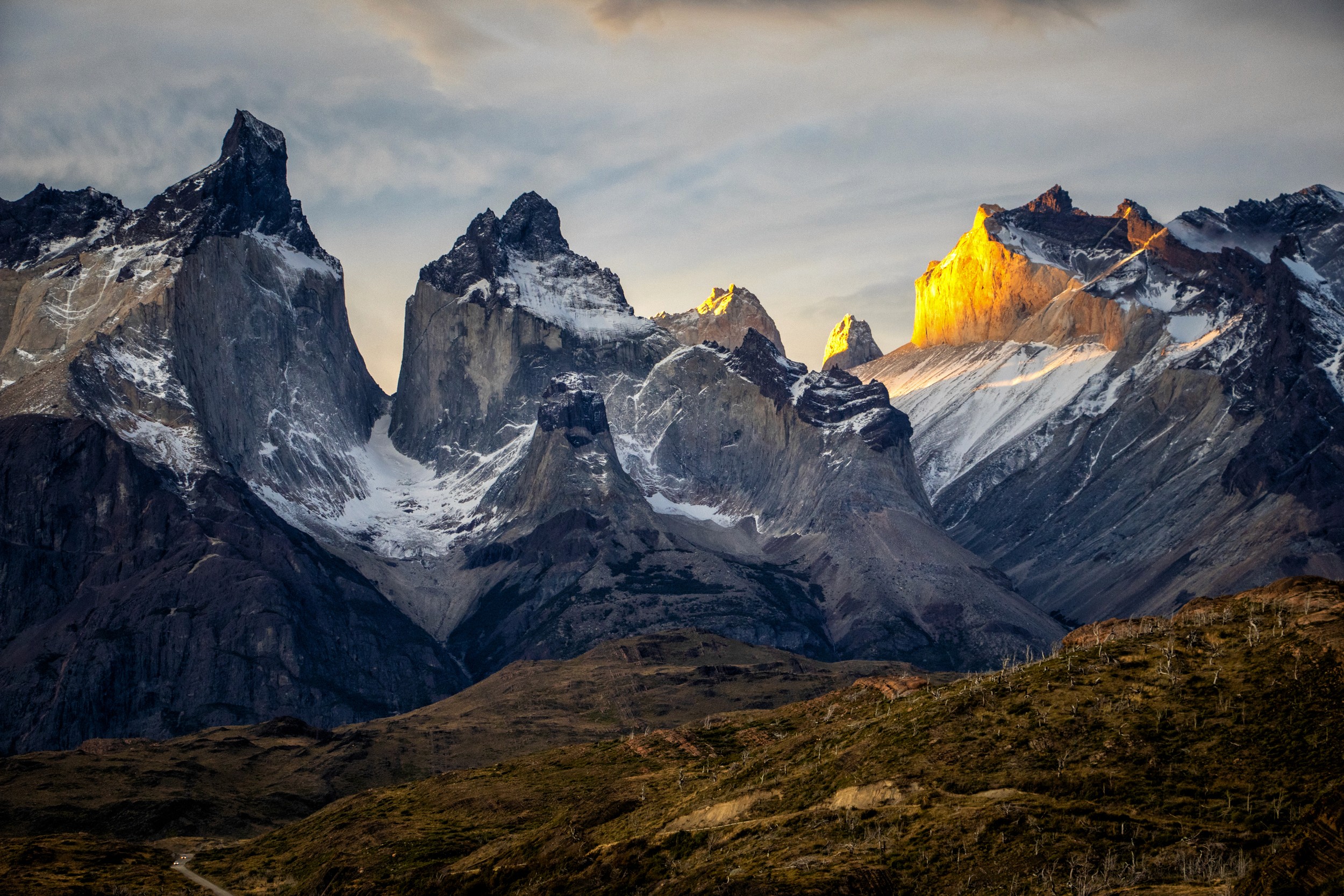 Sunlight strikes a jagged peak among the Torres del Paine mountains, illuminating it against shadowed ridges