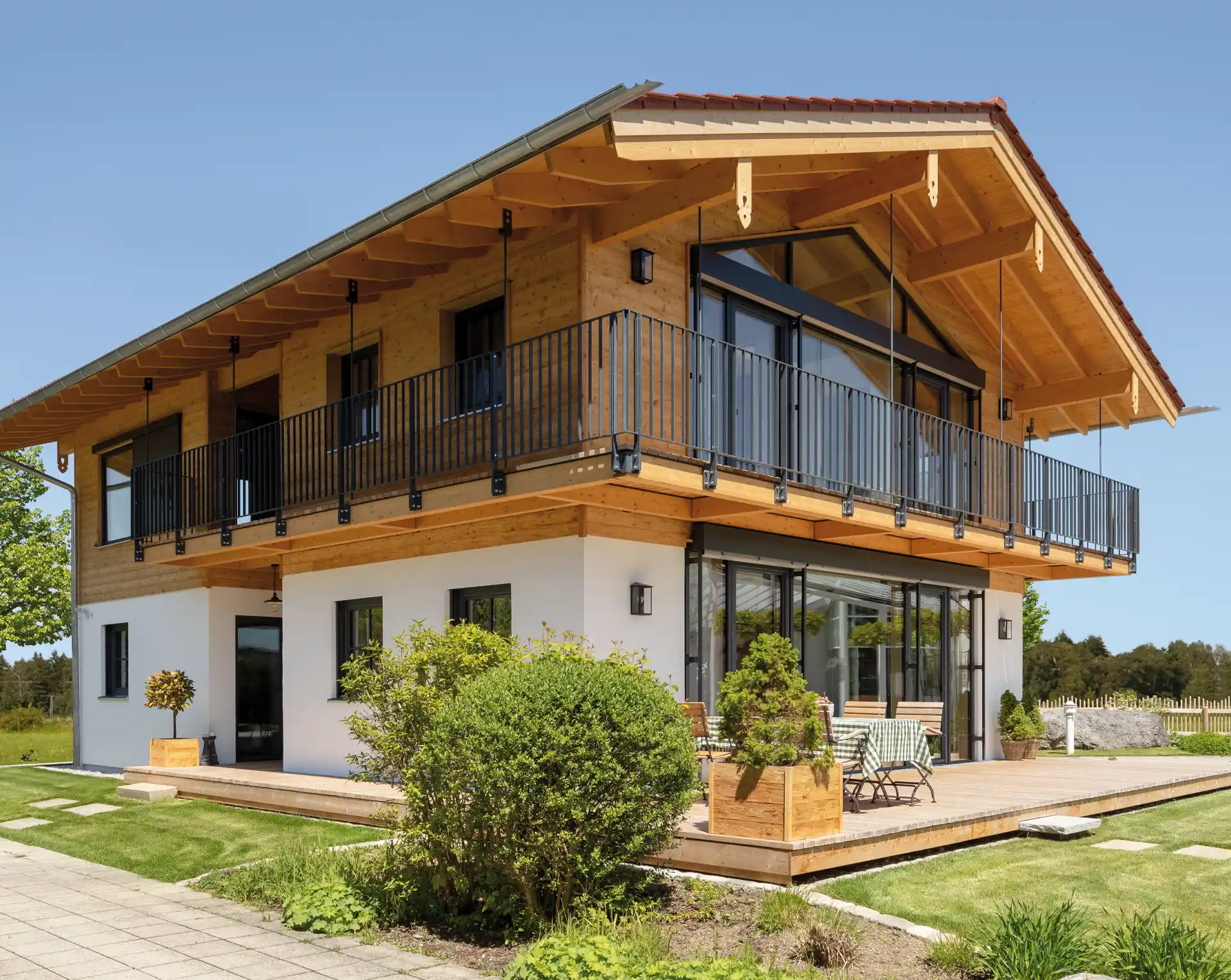 Modernes Holzhaus mit großzügigem Balkon, umlaufender Holzterrasse und viel Glas.