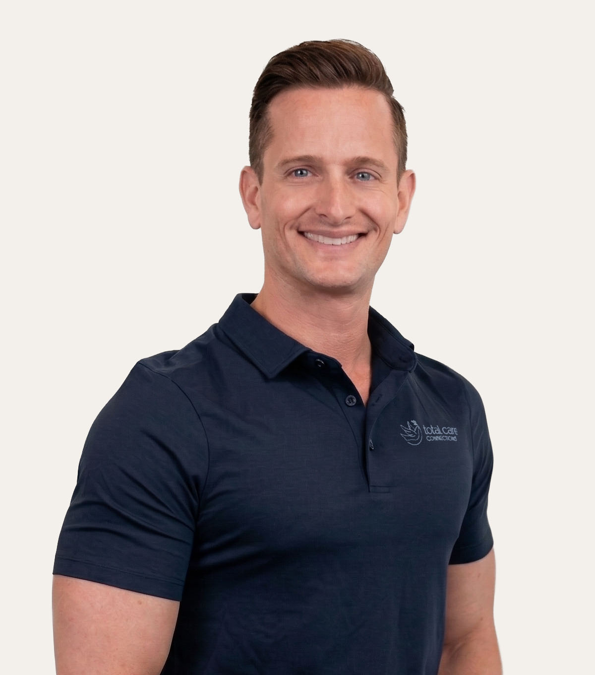 A man with short brown hair and a navy blue polo shirt with a logo on the left side of his chest.