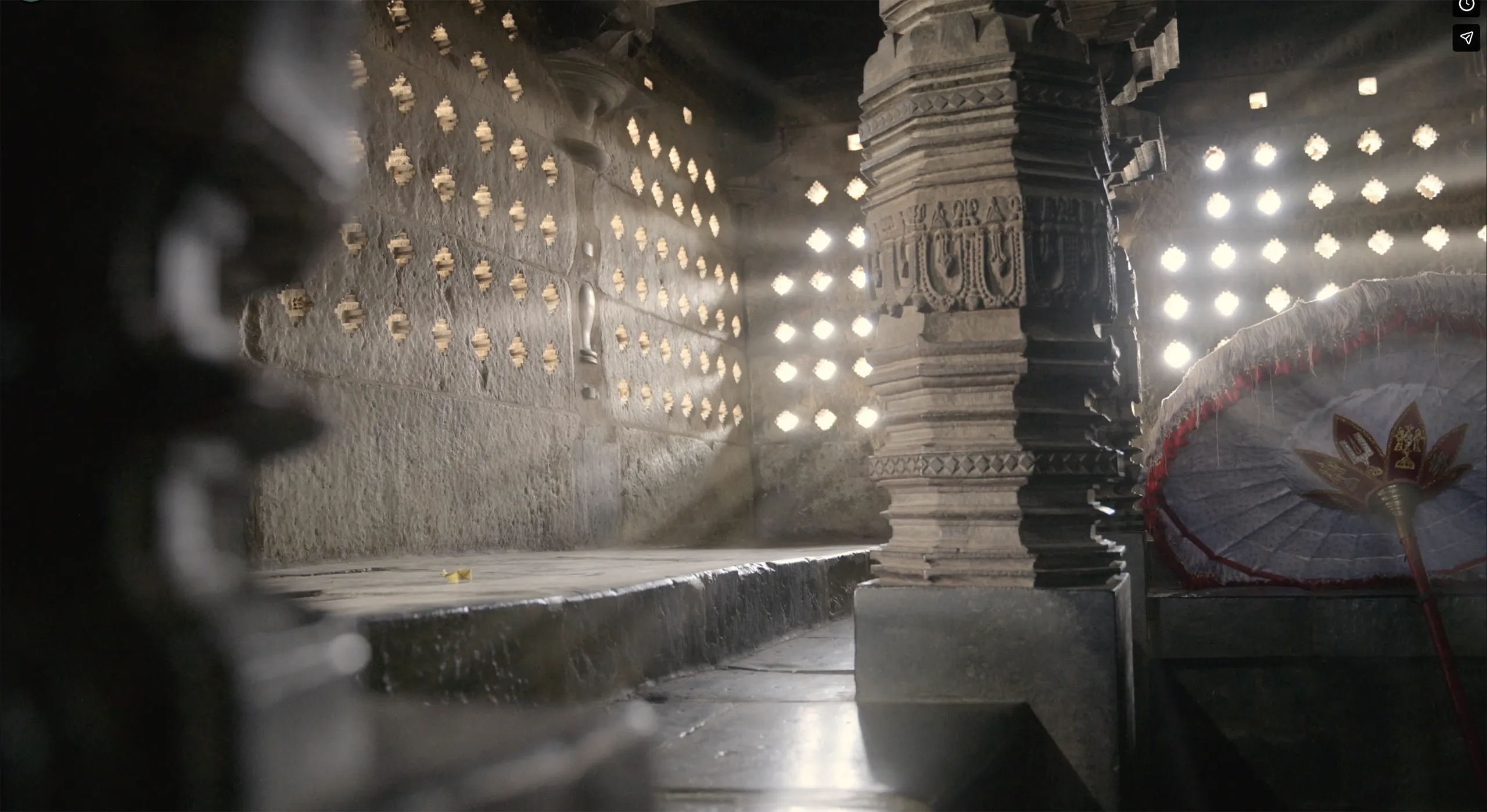 Cinematic interior shot of an ancient stone temple with dust motes dancing in beams of sunlight in Bangalore India.