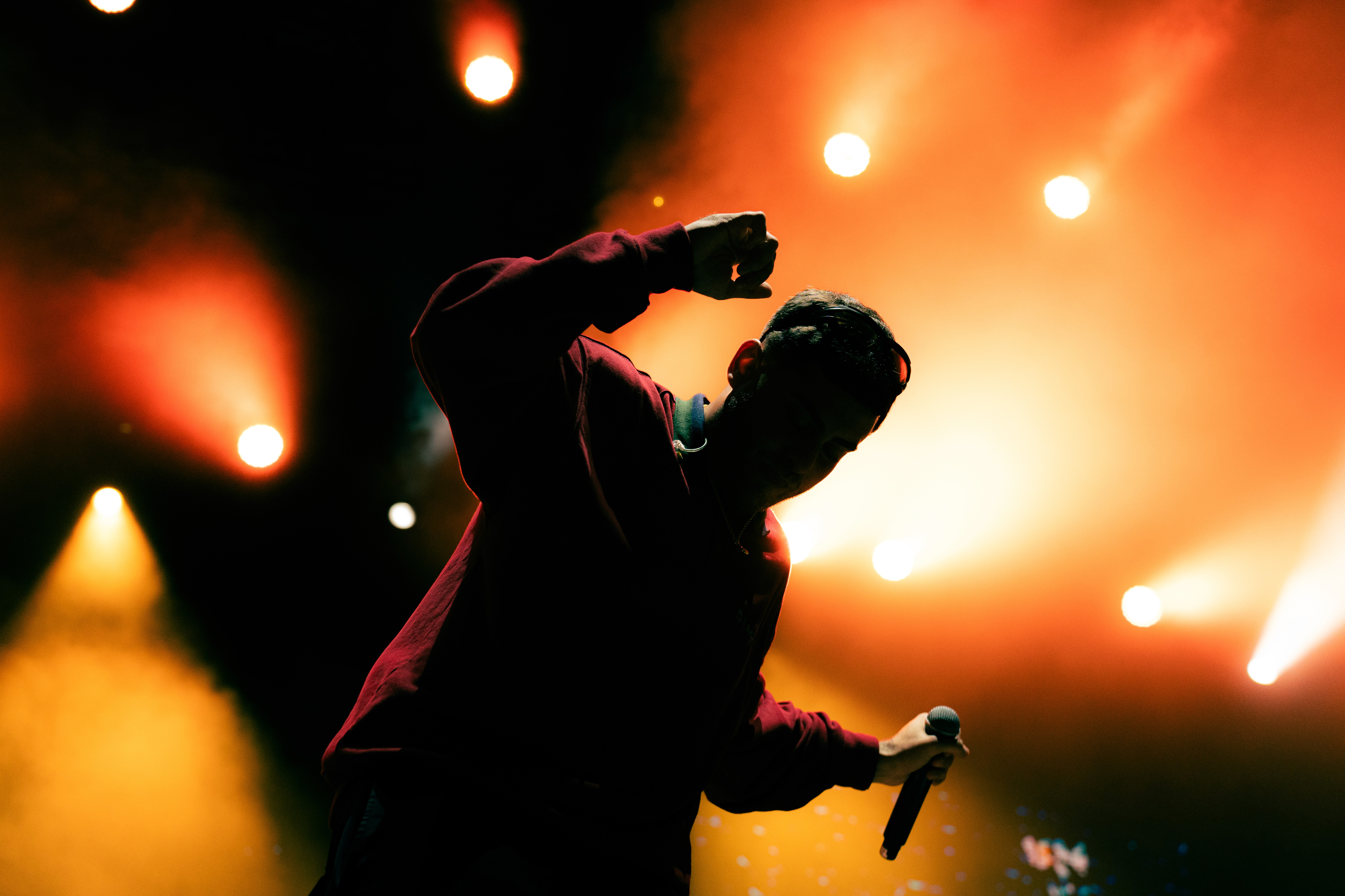 A woman wearing a shiny coat stands in focus, while a blurred background creates a sense of movement.
