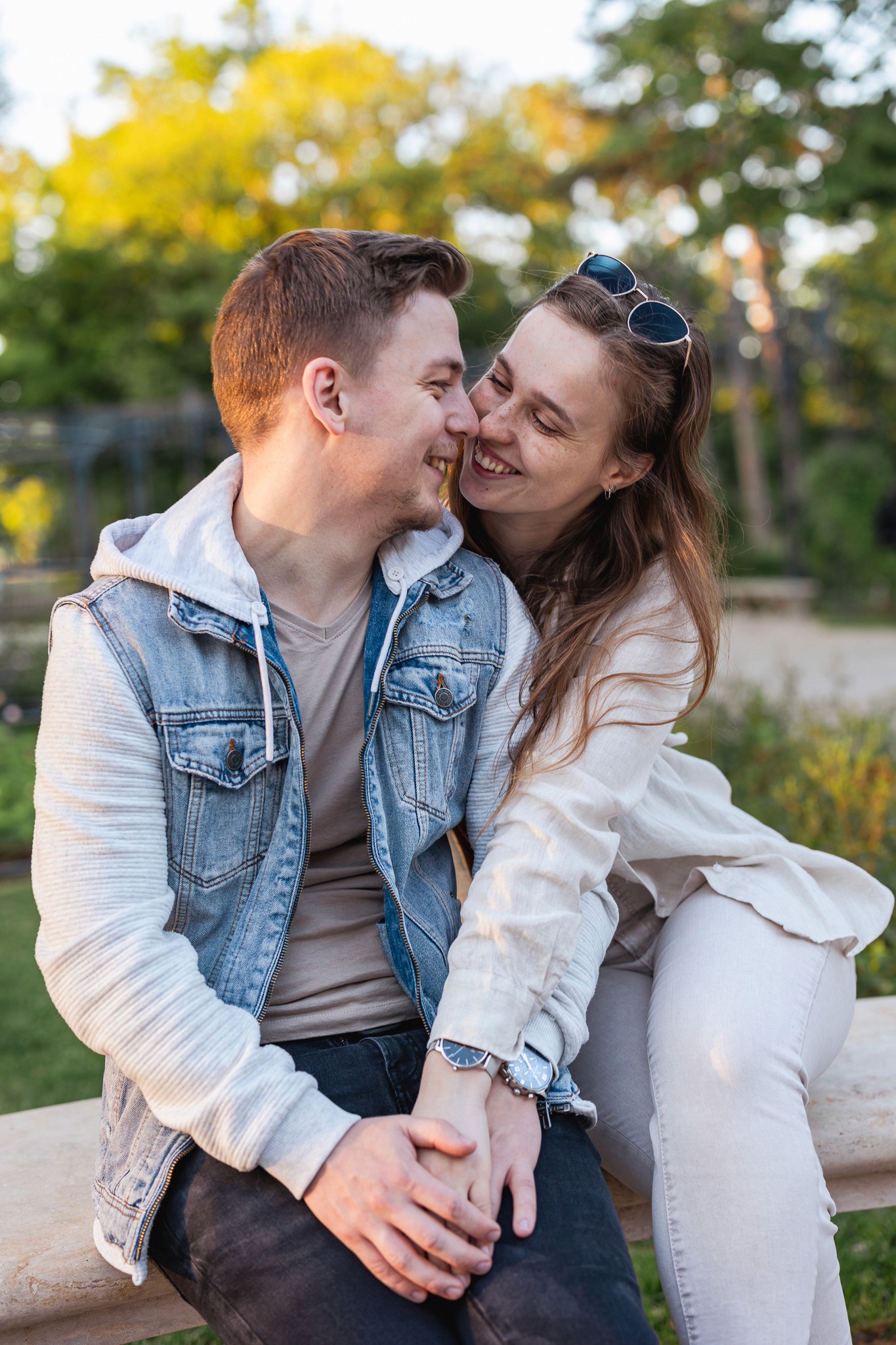 Egy pár ül egy padon, egymás kezét fogva, természetes környezetben.