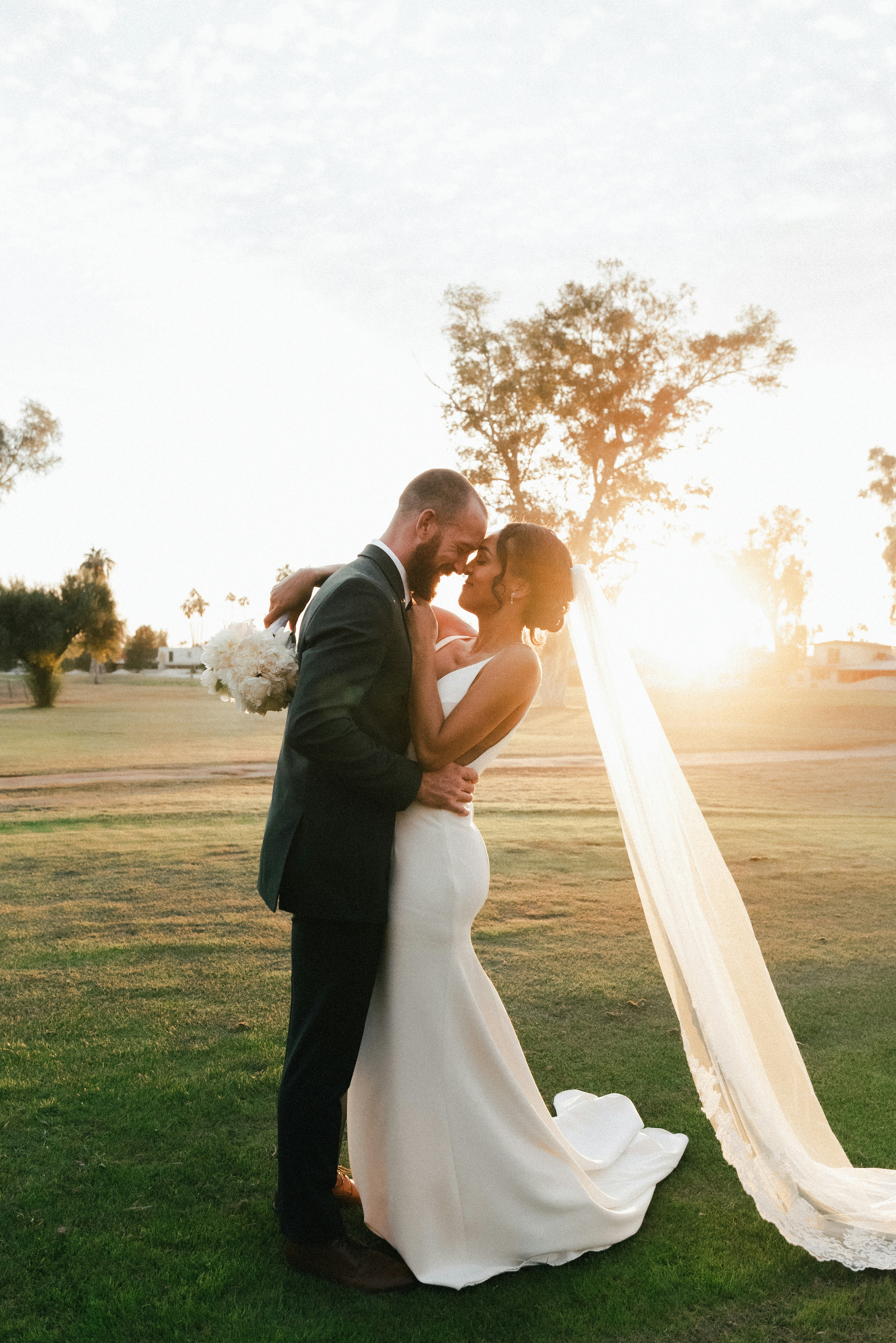 A couple stands outdoors at sunset.