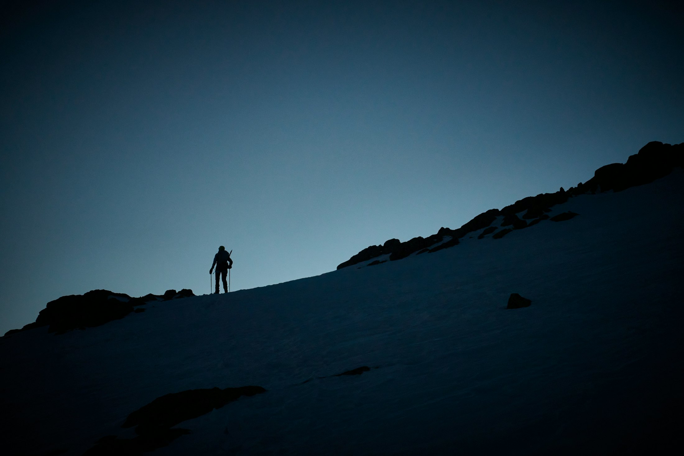 A lone ski tourer on a ridge line at dusk