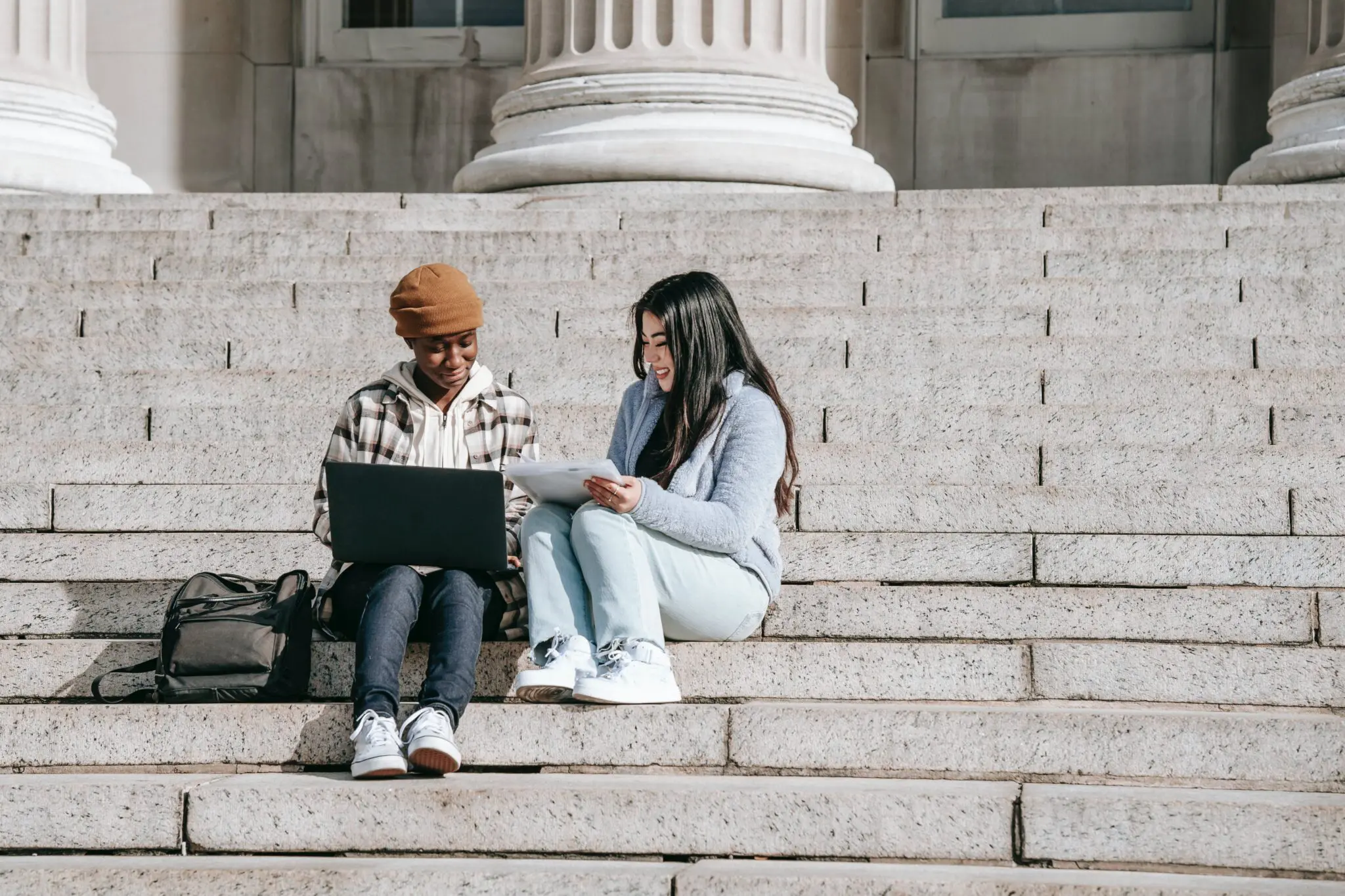 College students using laptop on university stair case