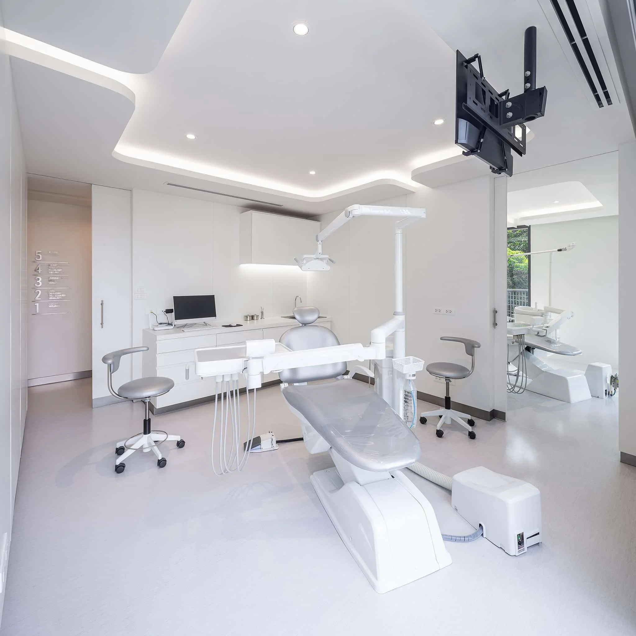 Treatment room with a dental chair and a wall-mounted screen