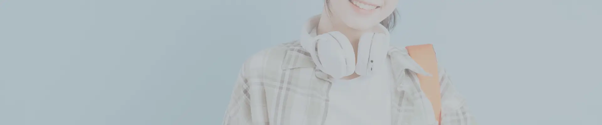 Smiling college student with headphones and backpack – showcasing tech and daily wear for a complete college packing list.