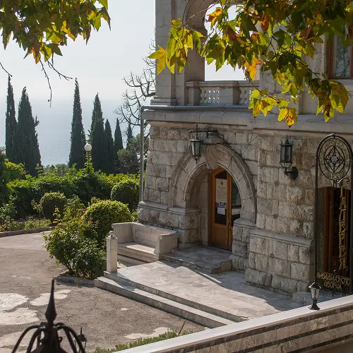 Stone entrance and steps of Sudeley Castle surrounded by lush gardens and greenery
