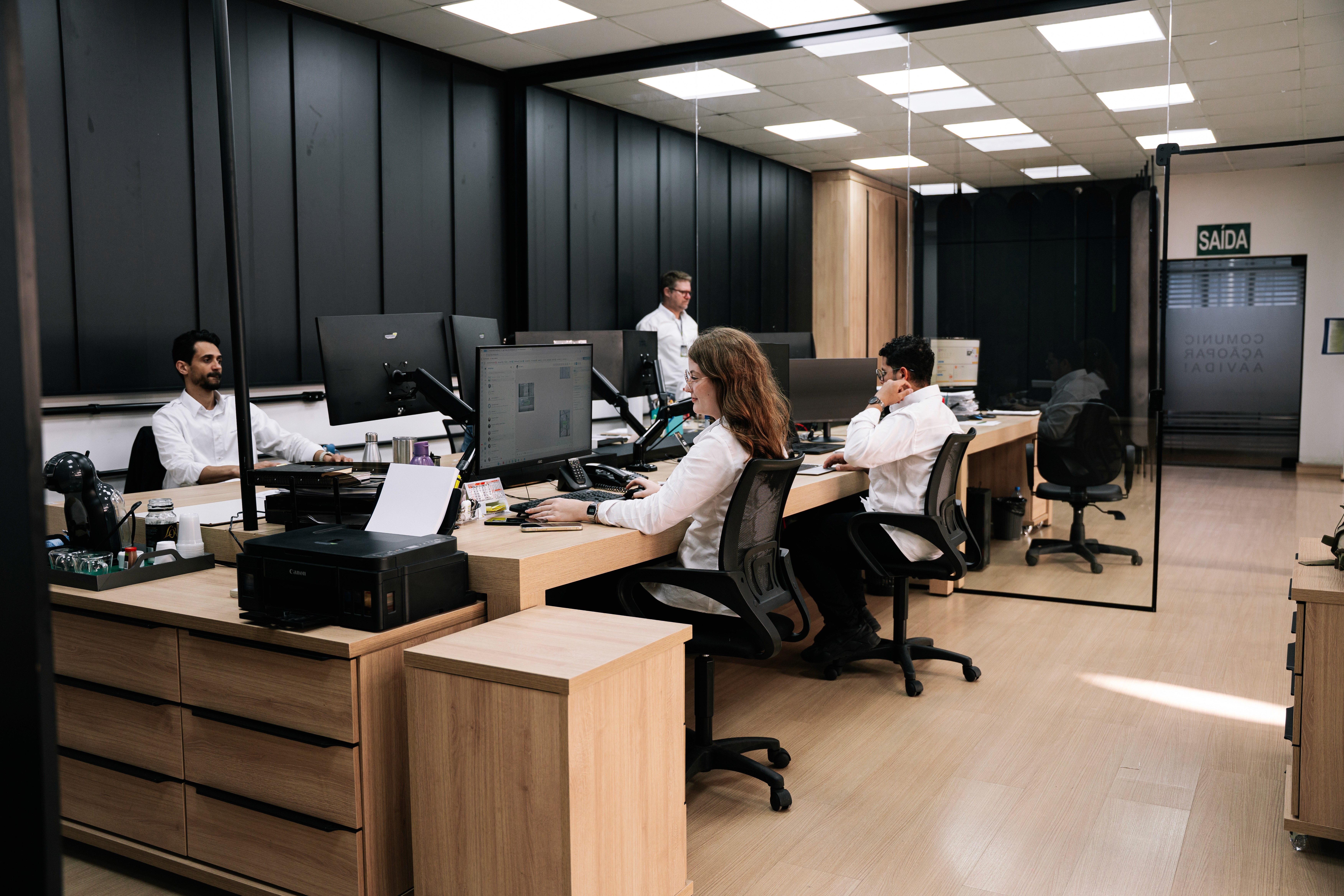 A large group photo of diverse team members gathered in an industrial-style space with arched ceiling.