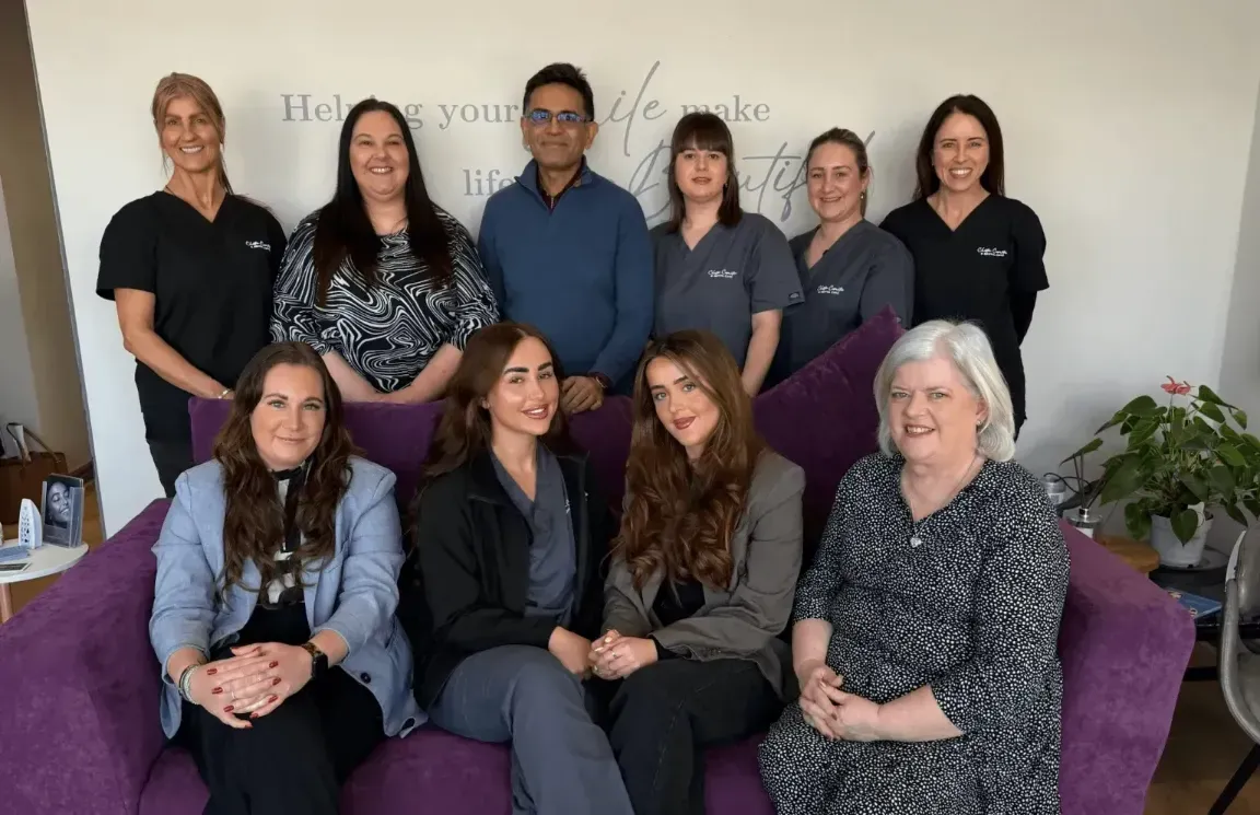 The Team of Dentist and Nurses at Chester Cosmetics & Dental Care sat on a couch and some standing behind