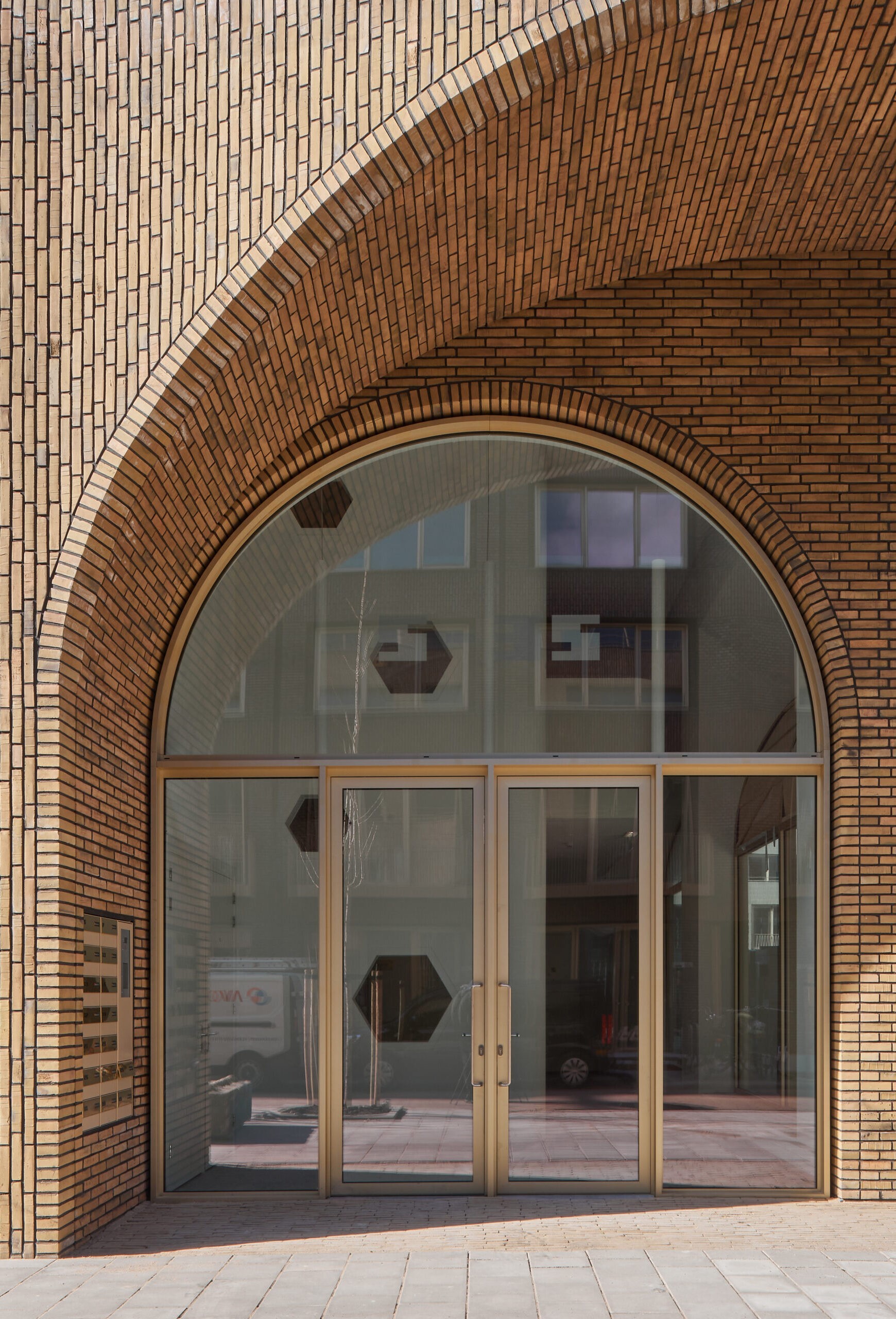 Boogvormige bakstenen portaal met glazen deuren