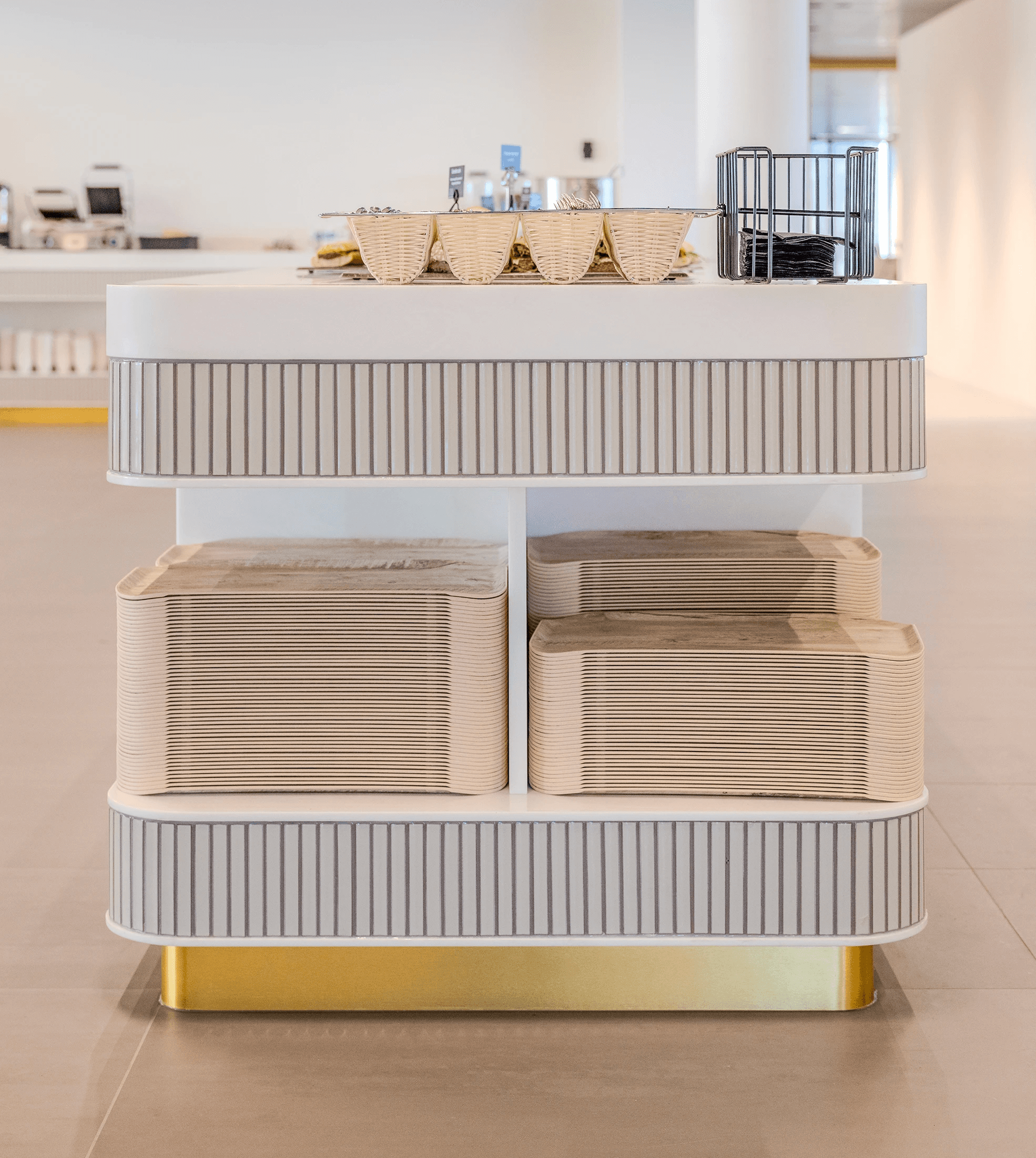 Wit serviesstation in de restaurantzone van AFAS DotNL met gestapelde borden, glazen en bestekhouders op een geribde goudkleurige voet – DSN Workspace Solutions