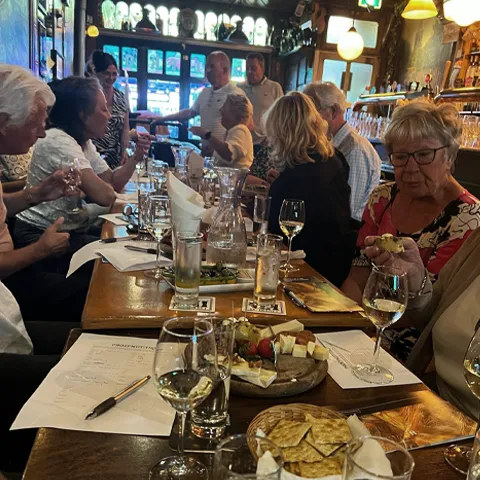 Gasten proeven witte wijn met een plankje kaas aan tafel