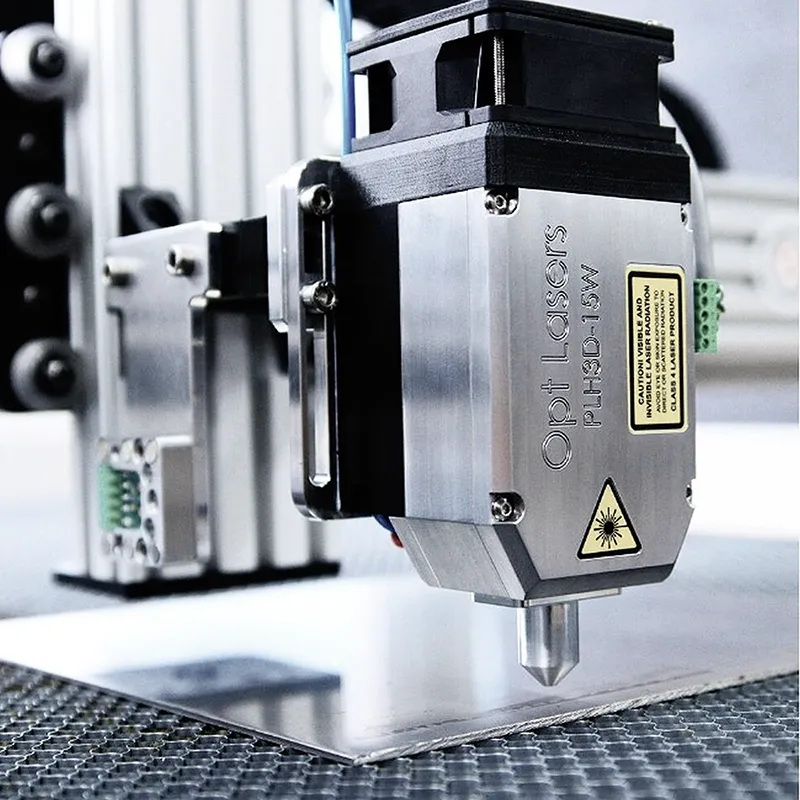 A smiling woman with her arms crossed, standing against a dark green background. She has long, dark hair.