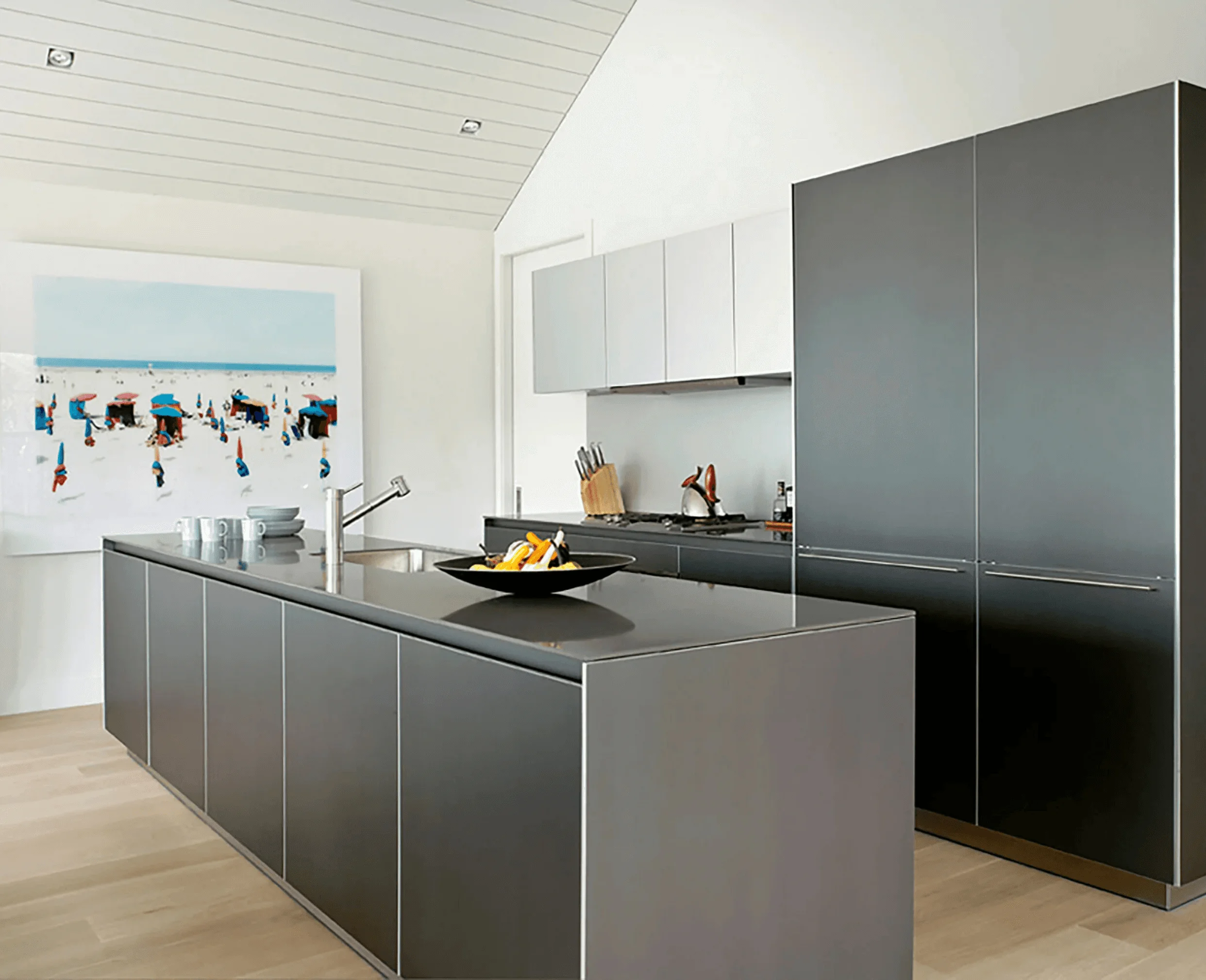 The cottage's kitchen island in matte gray cabinetry, with a beach-scene painting visible on the wall behind