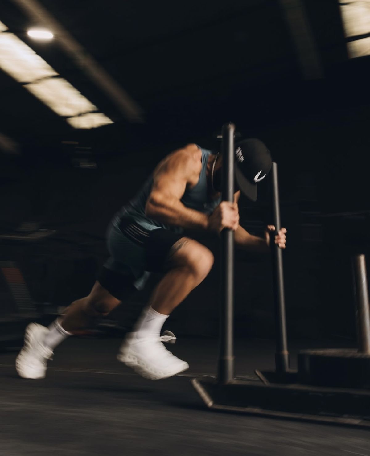 Man pushes a weight sled in a gym, motion blur shows intense effort.
