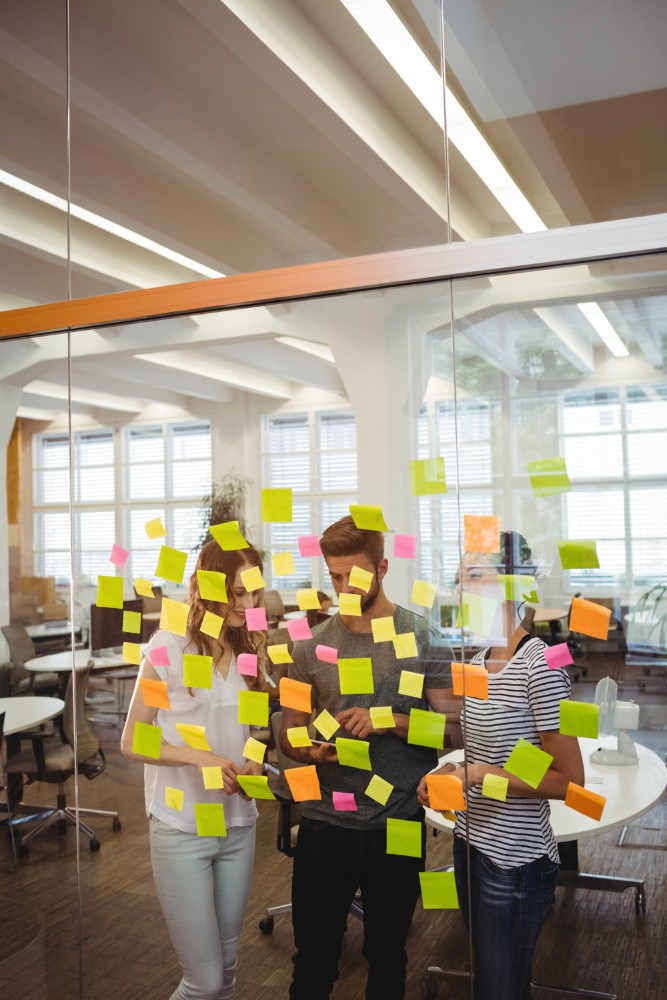 Close-up of colorful sticky notes on glass, used by a team for planning.