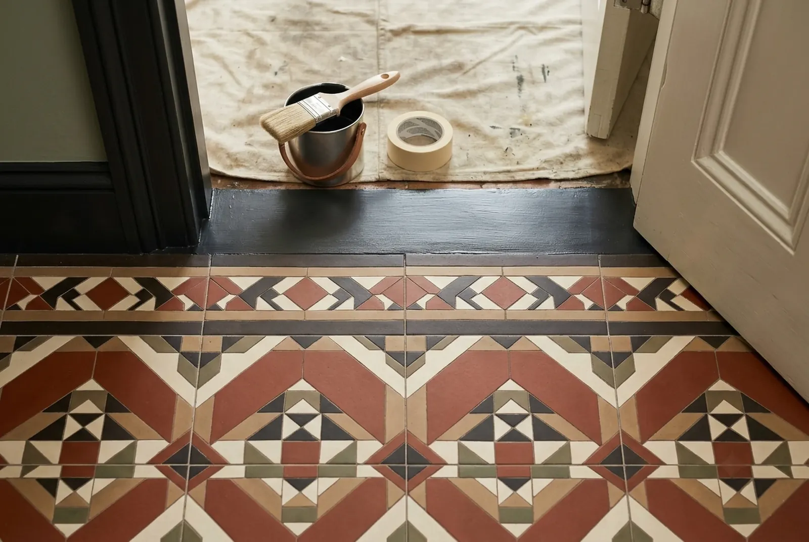 A Victorian geometric tiled hall floor meeting a newly painted off-black threshold