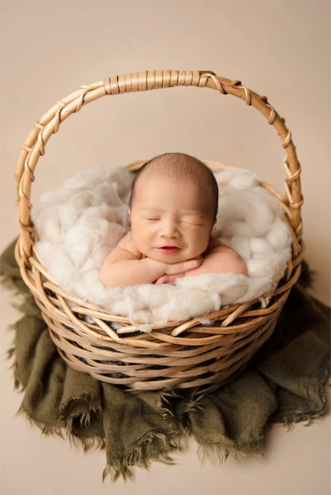 Smiling newborn resting in a wicker basket