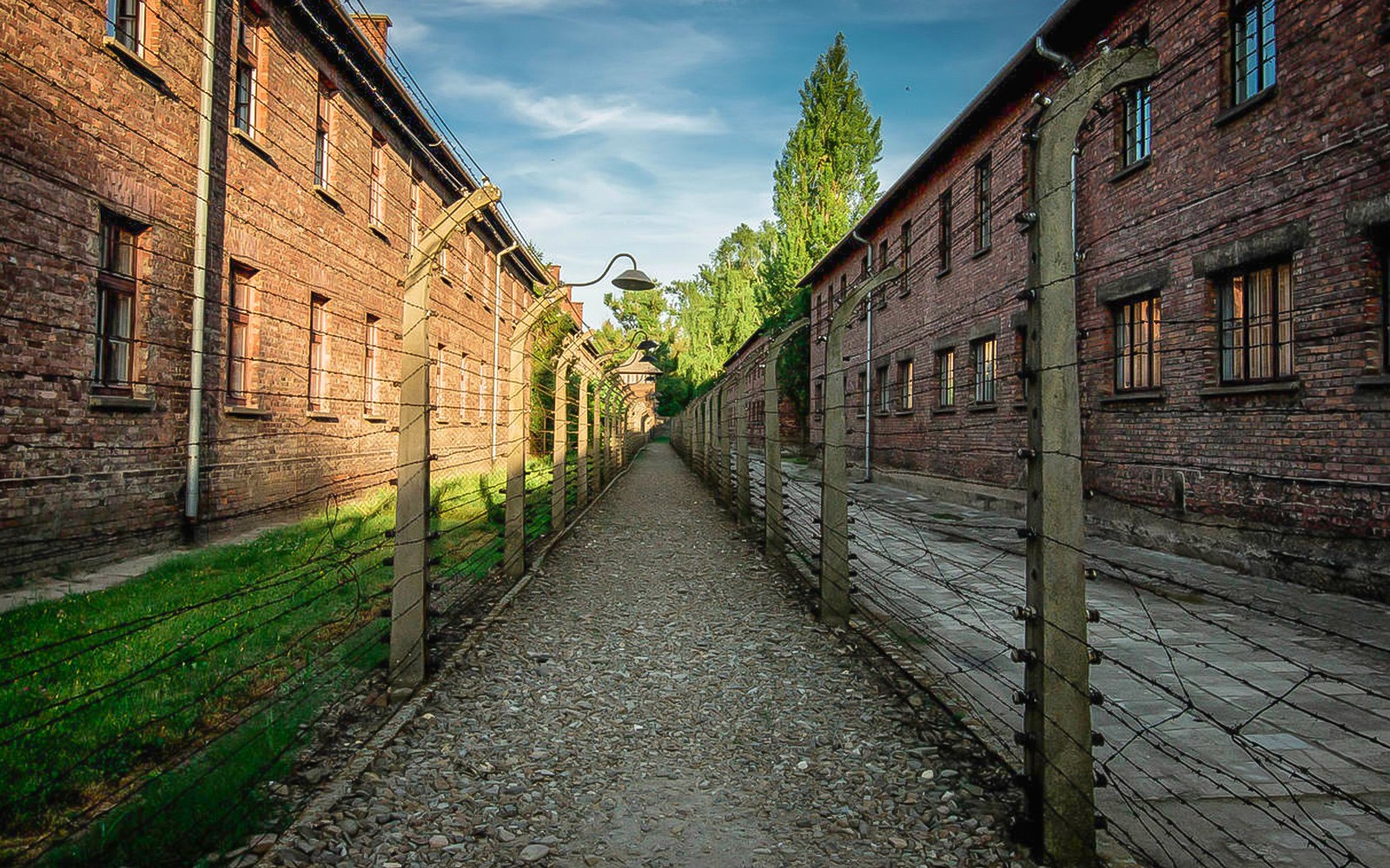 Camino entre edificios de ladrillo y cercas de alambre de púas en Auschwitz, Polonia.