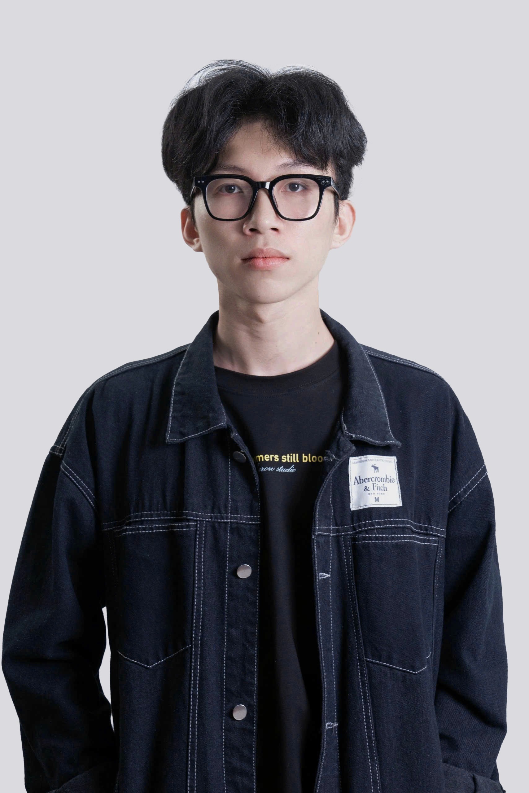 A thoughtful young person with dark hair gazes to the side, captured in soft black and white lighting.