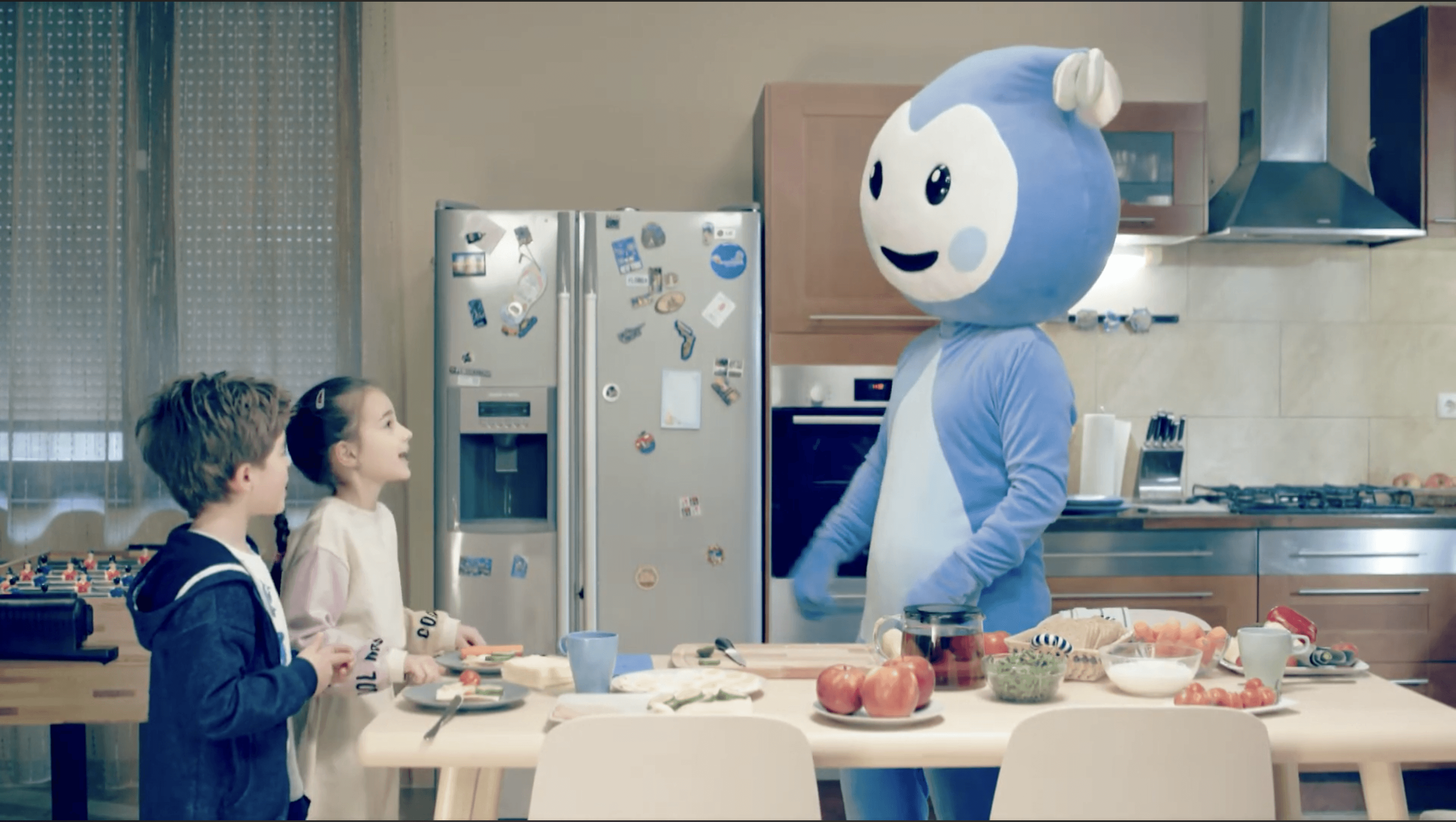 Cseppbarát kék kabalafigurája megterített asztalnál tanítja a gyerekekt a konyhában.