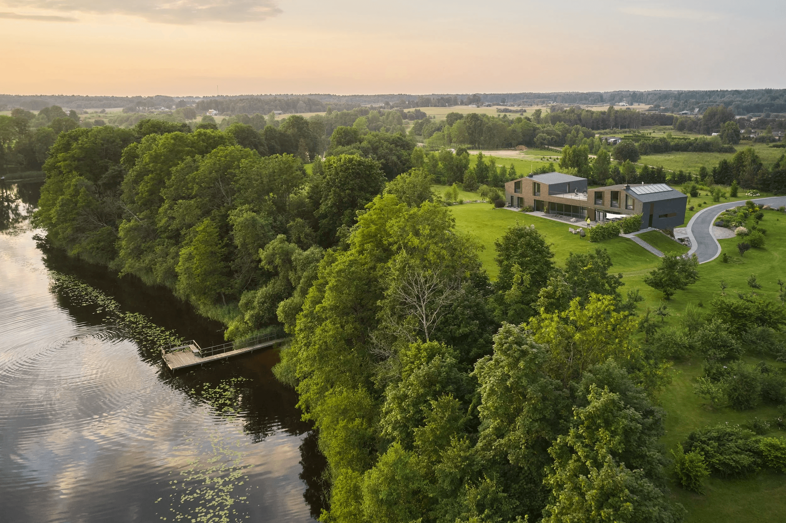 An elegant wedding ceremony setup features a domed gazebo adorned with peach and pink floral arrangements and lush greenery. White chairs line the aisle.