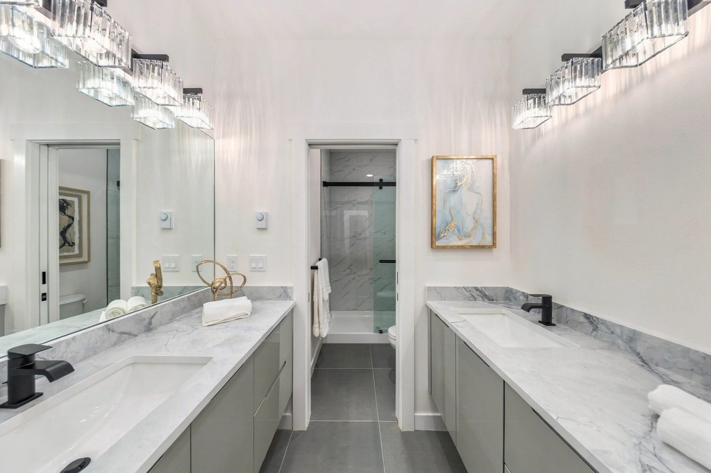 Primary ensuite with twin vanities, crystal sconces and shower beyond