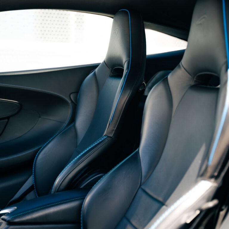 Spacious and comfortable rear seating area of the blue McLaren GT, showcasing interior details.