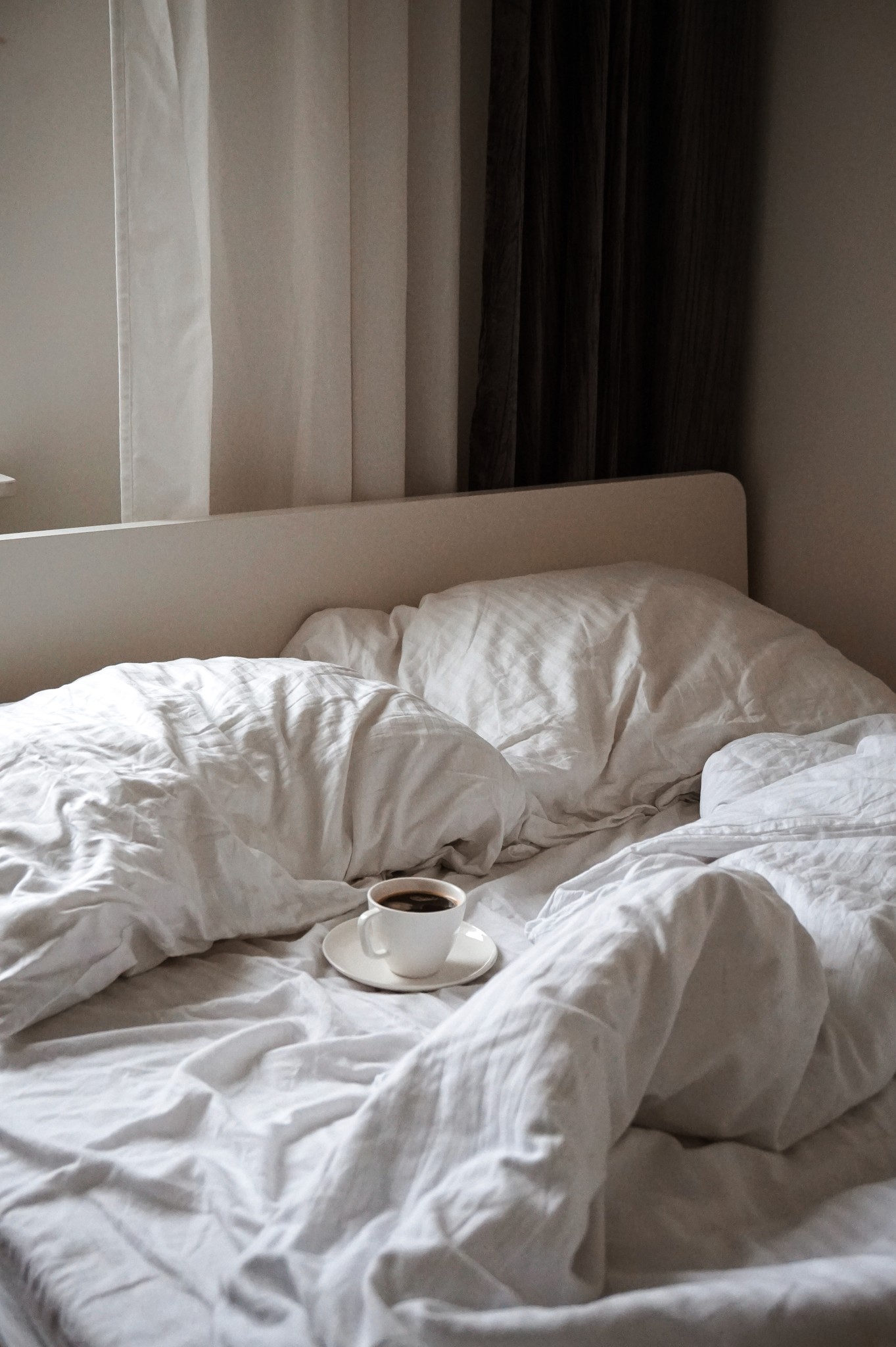 Image of a bed with a cup of coffee sitting on it