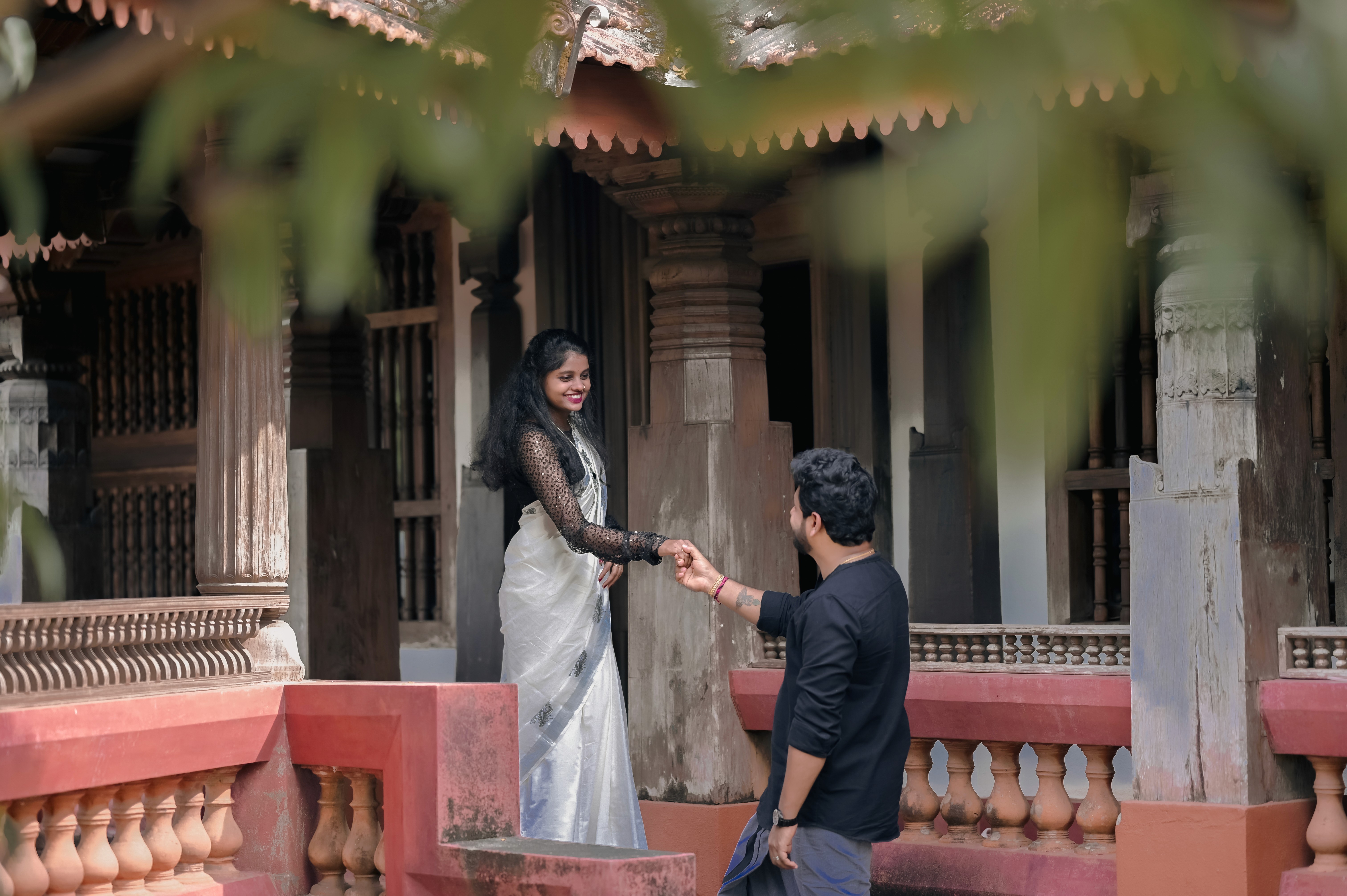 Couple holding hands at a traditional courtyard house, framed by wooden pillars