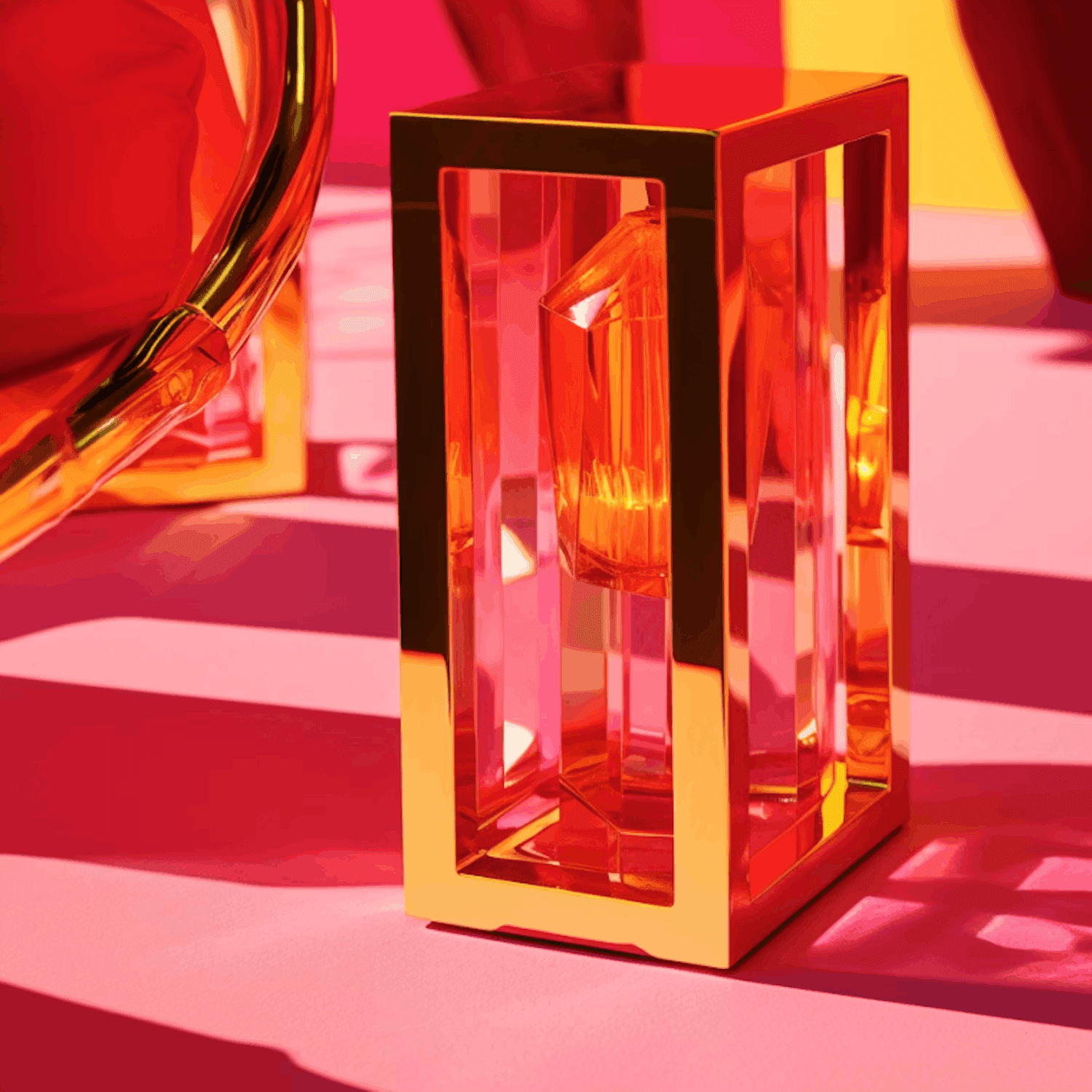 Golden-framed, faceted red perfume bottle on a vibrant pink surface.