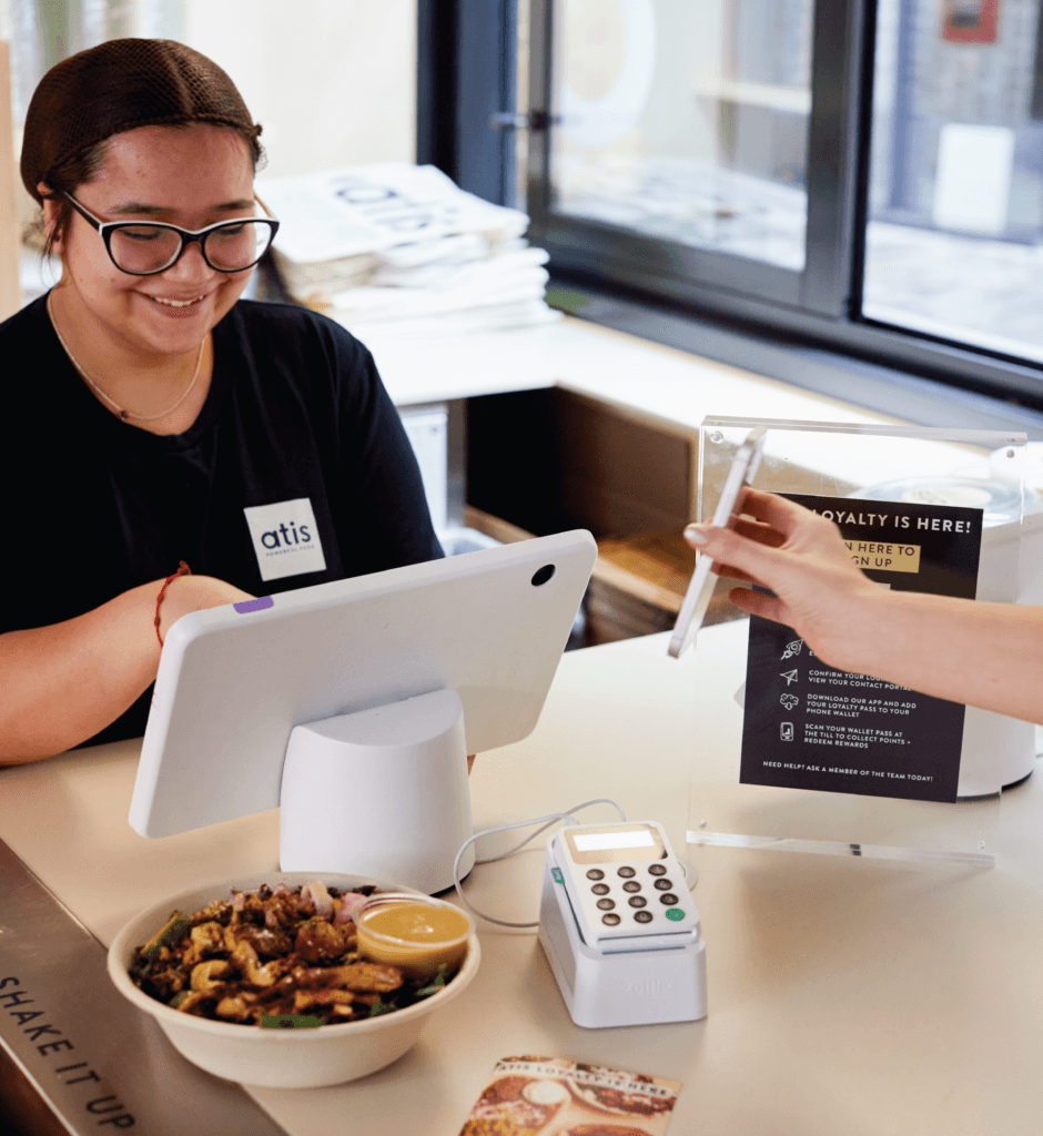 Image of someone showing a phone at a cash registrer at Atis