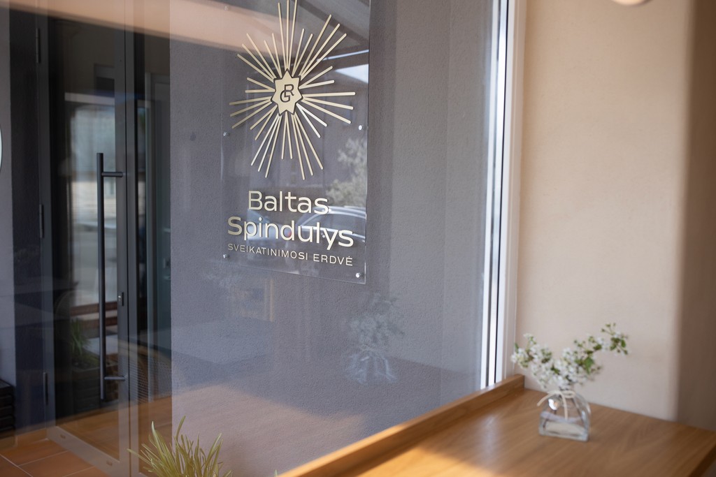 Baltas Spindulys sveikatinimo erdvės įėjimas Marijampolėje su logotipu ant stiklo