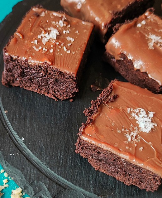 Close-up shot of brownies with chocolate icing and salted flakes on top